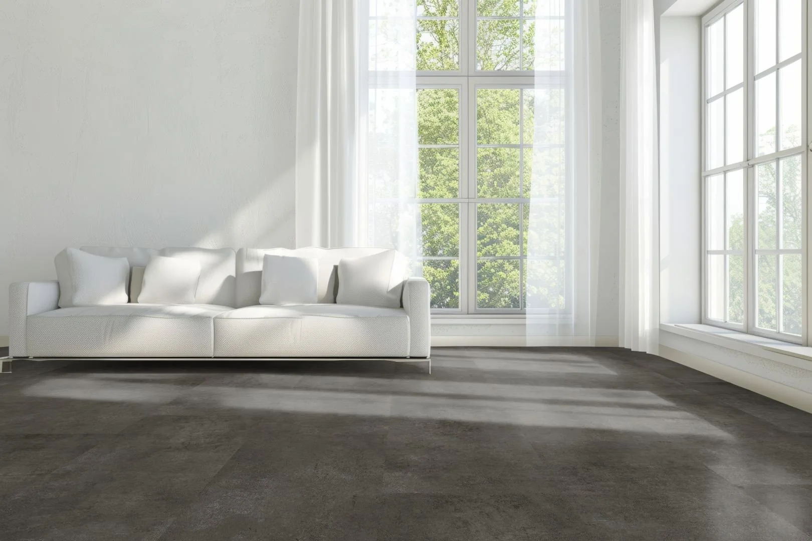 Modernes Wohnzimmer, lichtdurchflutet mit weißer Couch, hellen Wänden und dunklem anthrazitfarbenen Schieferboden. 