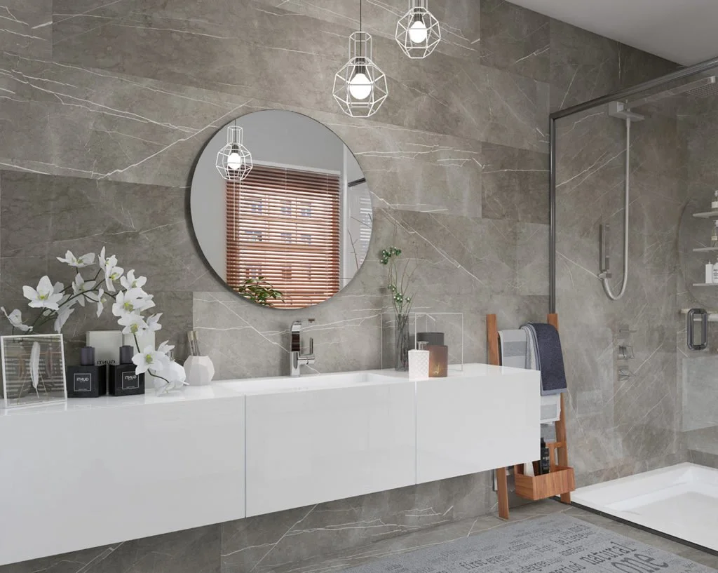 Modernes Badezimmer mit grauen Marmorwänden, weißem Waschtisch, Spiegel, Pflanzen und Duschbereich mit Glastür.