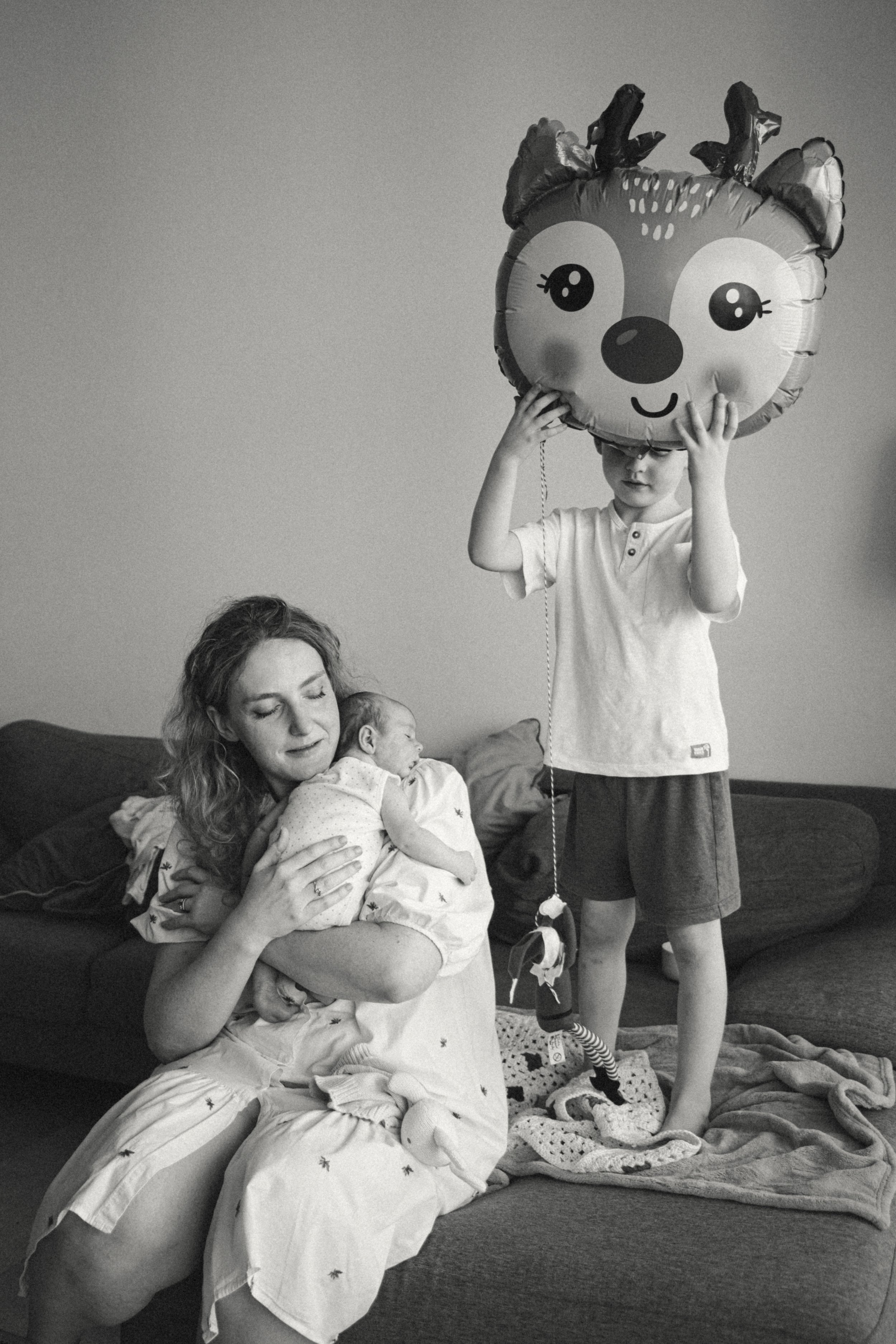 Mother holding her baby with her young son during an at-home family photography session in Dubai.
