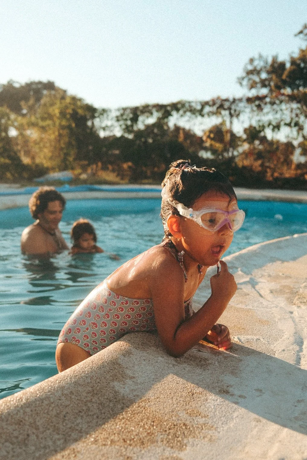 Children playing in a swimming pool during a candid family photography session in Dubai.