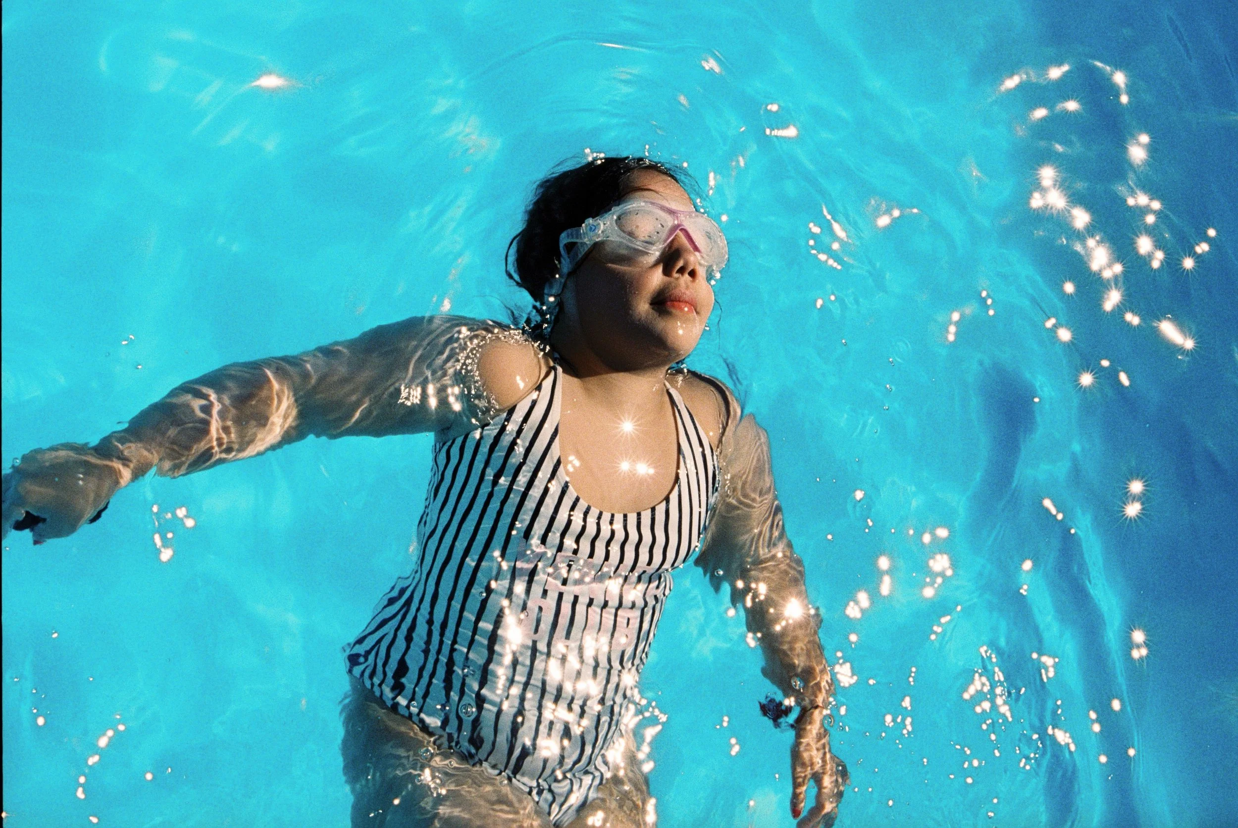 Woman floating in a swimming pool during a relaxed lifestyle photography session in Dubai.