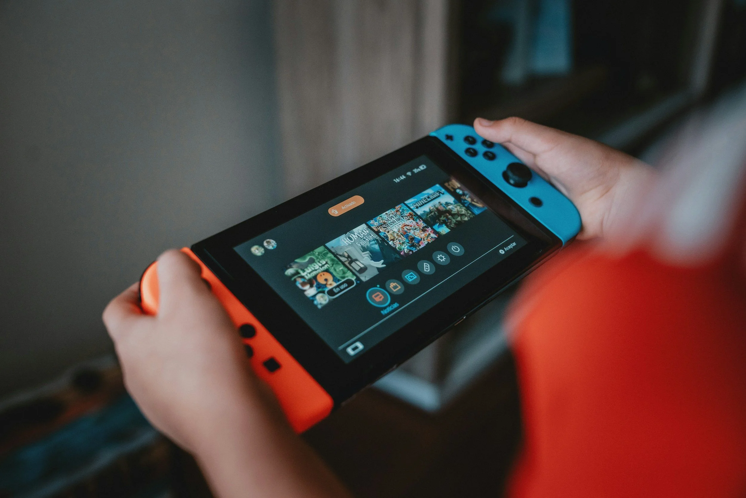 A person holding a Nintendo Switch gaming console, displaying a selection of video games.