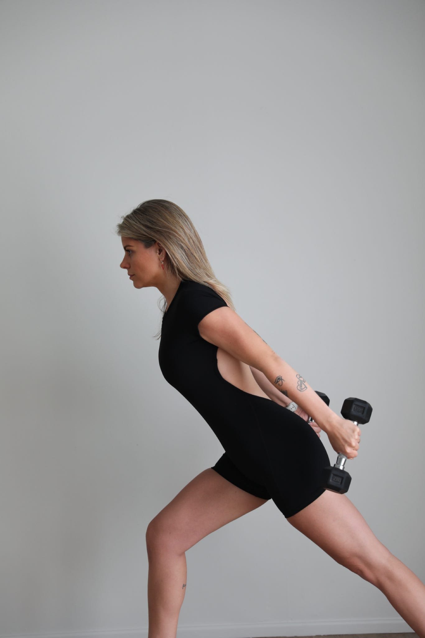 Woman demonstrating a lunge exercise with a dumbbell during Hot HIIT Pilates training