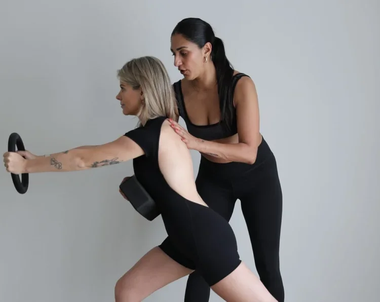 Instructor demonstrating alignment technique during a mat pilates class