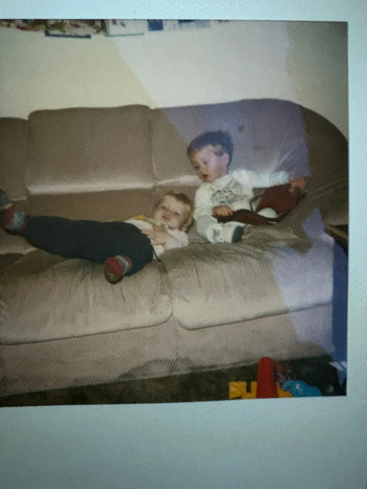 Two young cousins relaxing together on a sofa at home during childhood.