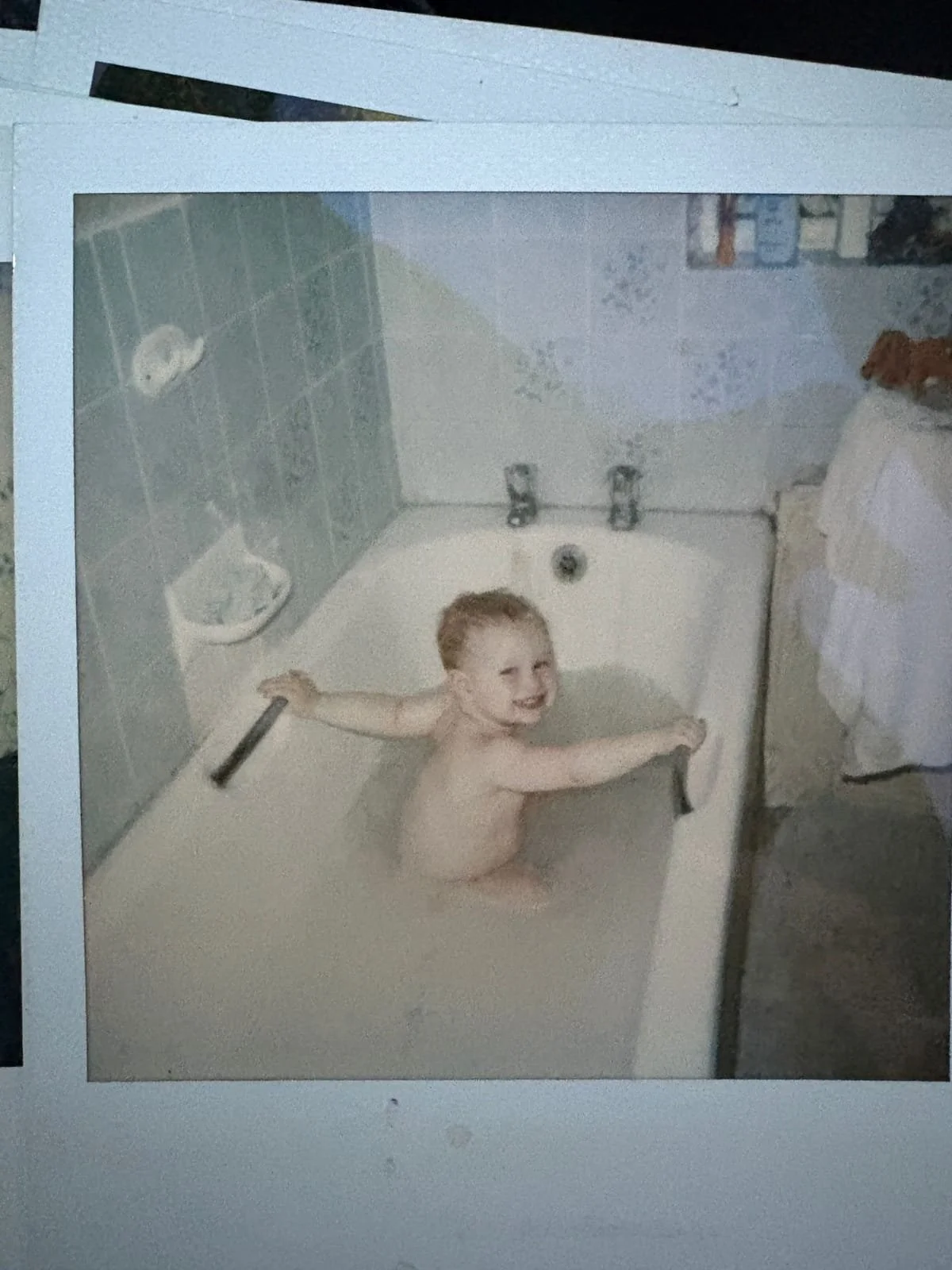 Young child smiling in a bubble bath at home, surrounded by thick white bubbles in a family bathroom.