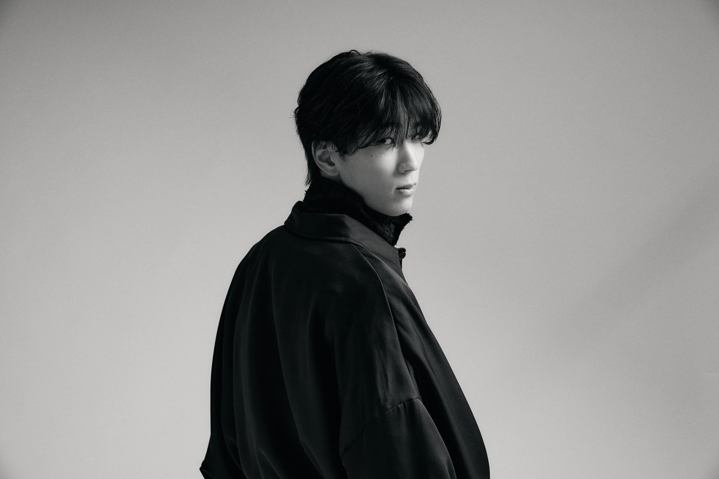 黒いジャケットを着た男性の横顔のポートレート写真（カラーグレースケール）」}