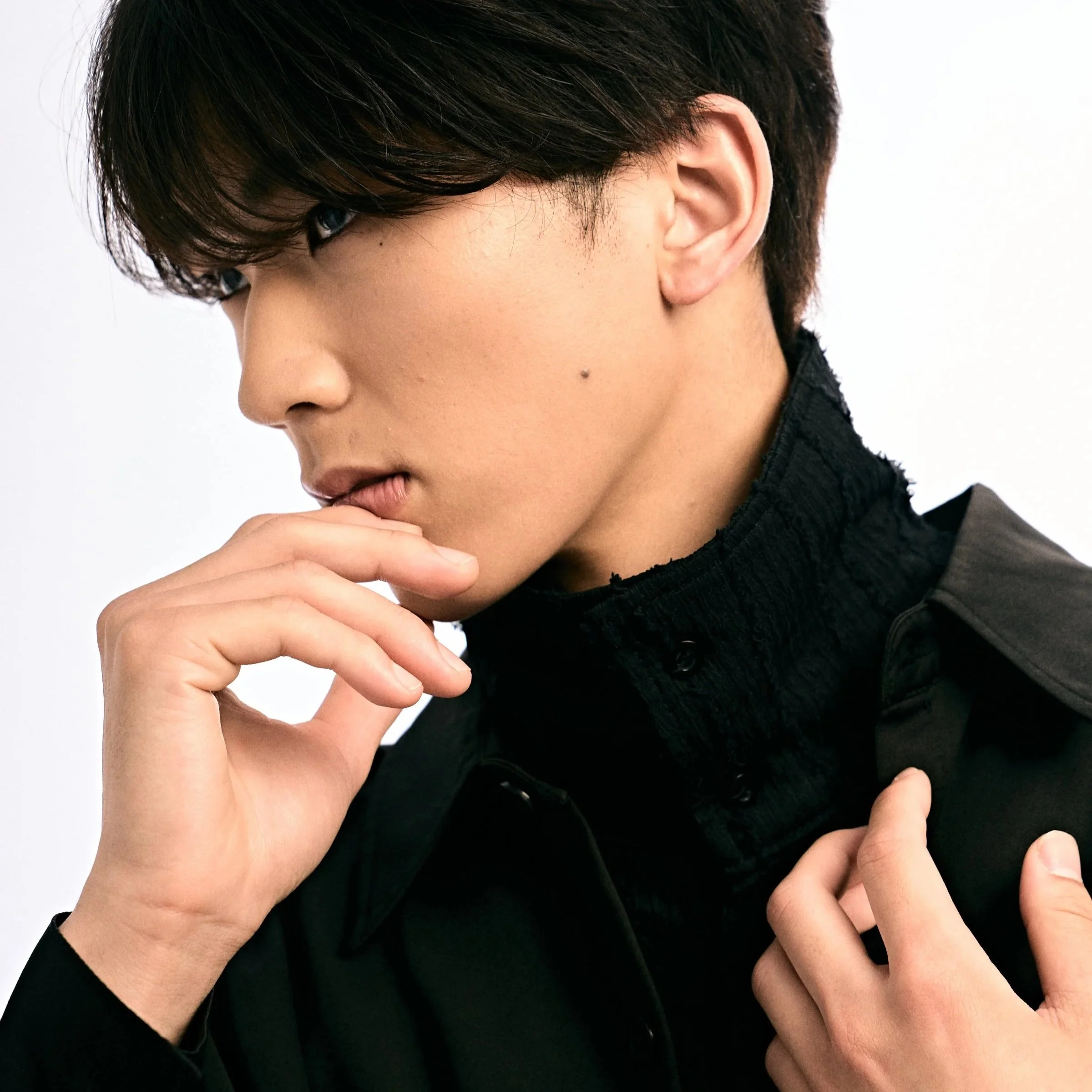 黒い服を着た人の横顔と手があごに触れているシルエット。白い背景。