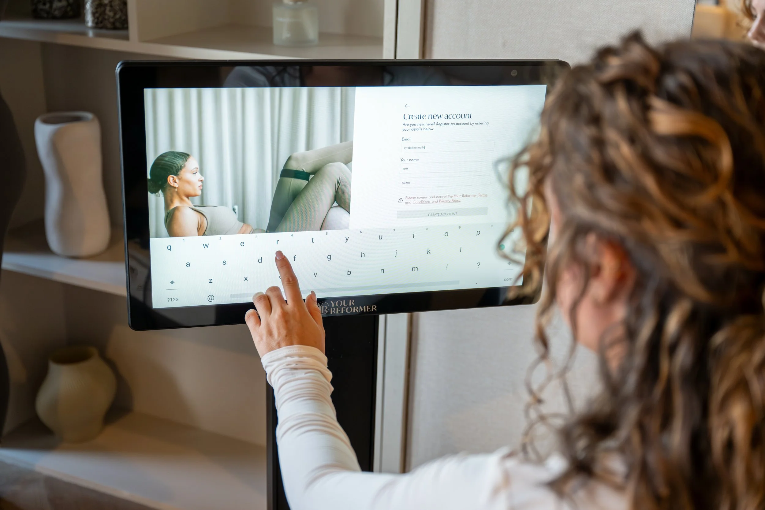 een vrouw die een les uitzoekt en op een reformer pilates bank zit