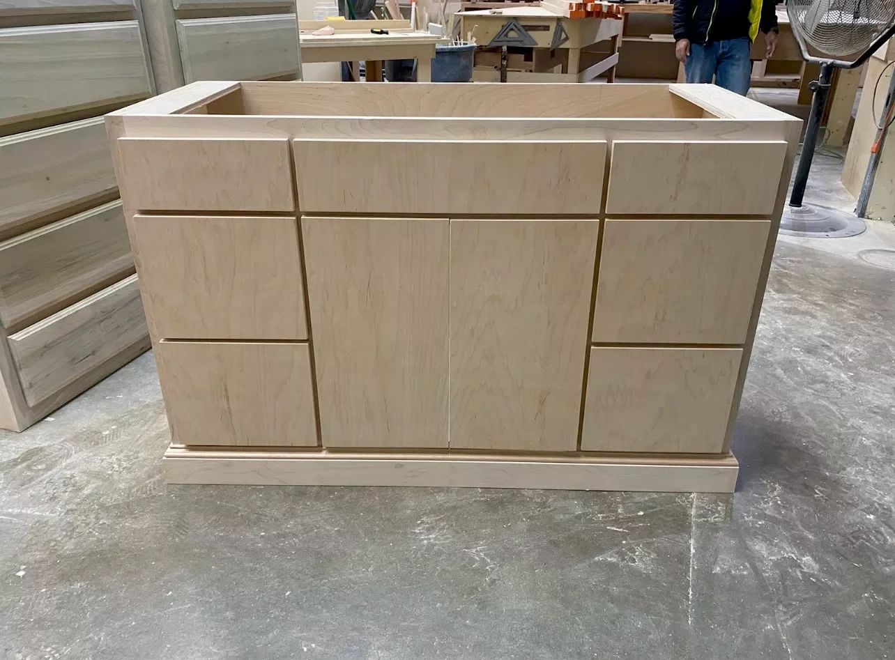 Unfinished wooden cabinet in a woodworking shop.