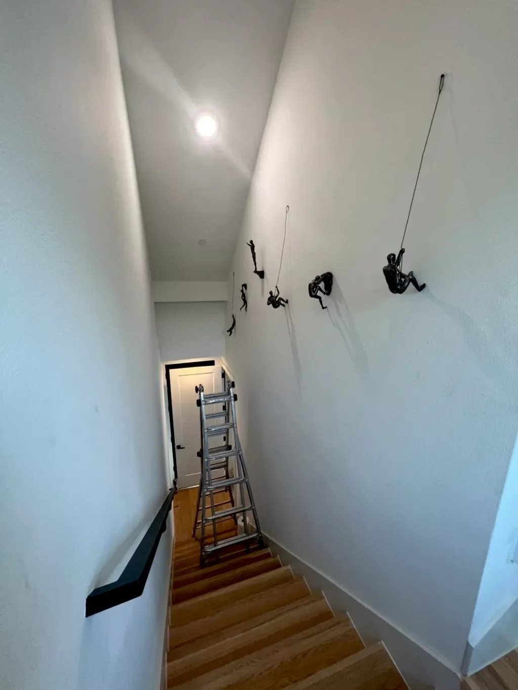 Hallway with wall-mounted climbing holds and a ladder at the bottom.