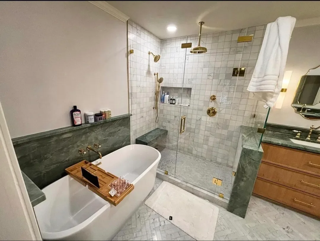 A luxurious bathroom with a freestanding bathtub, marble accents, and a glass-enclosed shower with gold fixtures.