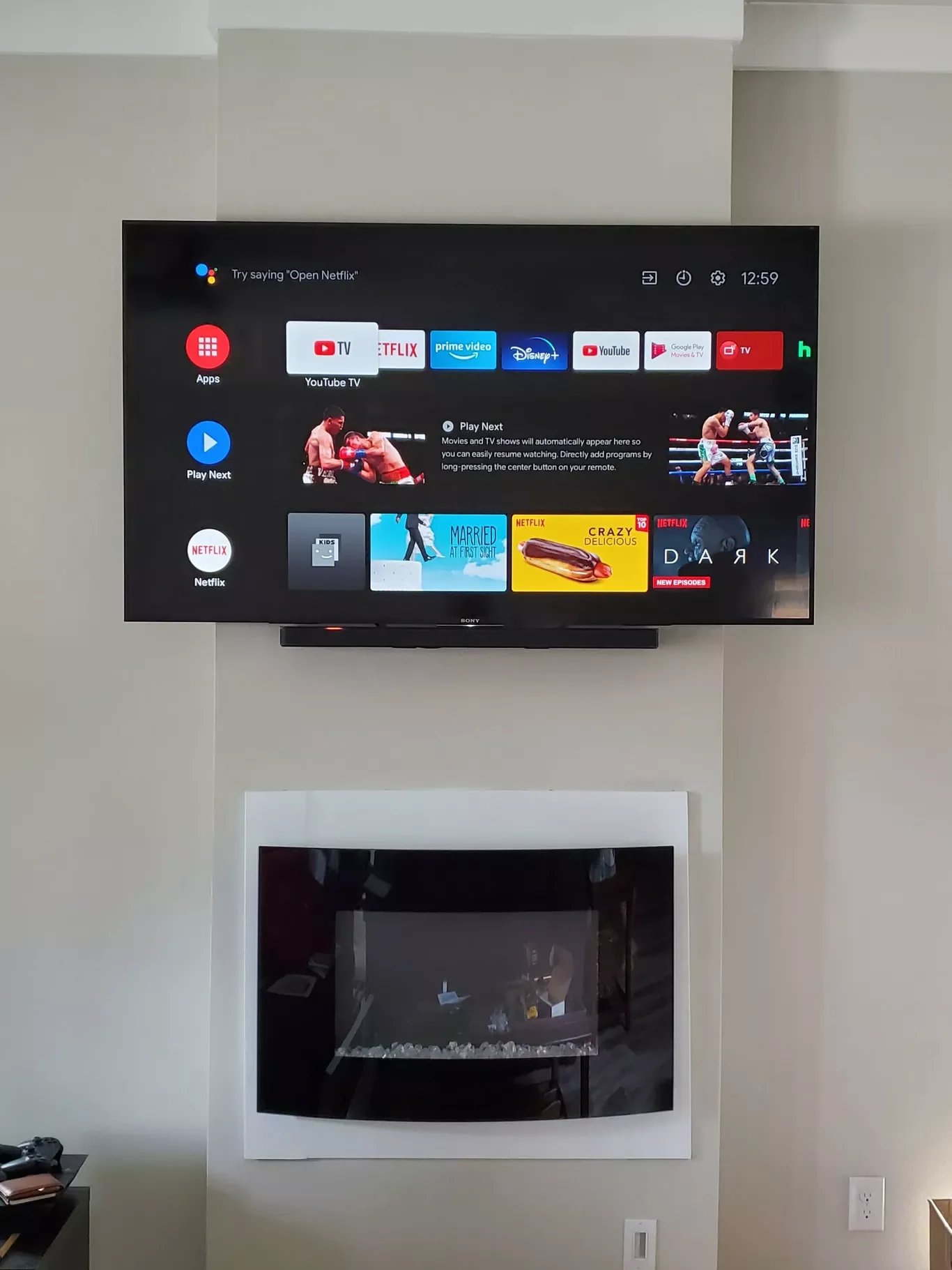 A wall-mounted flat-screen television displaying streaming app interface, with a fireplace below it.