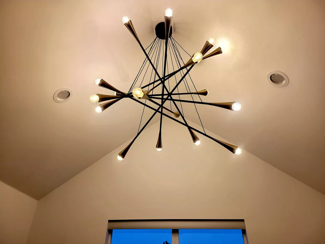 Modern chandelier with multiple arms and exposed bulbs hanging from a ceiling.