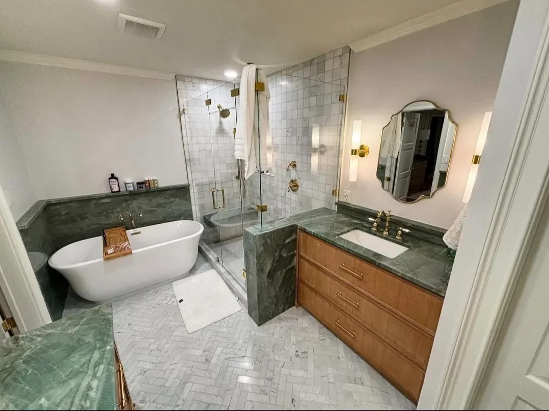 Bathroom with a freestanding bathtub, a glass-enclosed shower, and a wooden vanity with a green marble countertop.