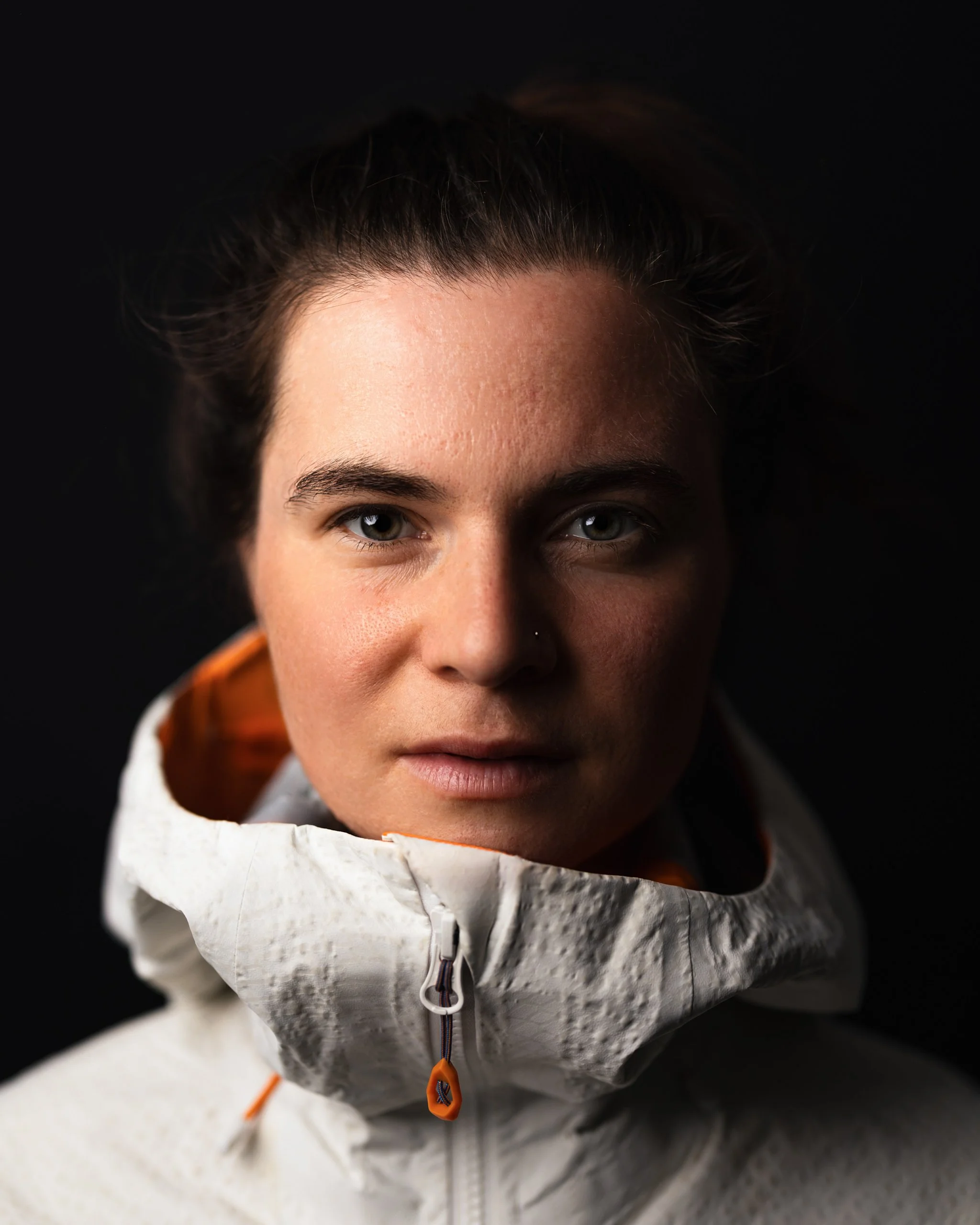 Ein Portrait aufgenommen mit Blitzlicht im Studio von einer Frau in Mammut Regenjacke