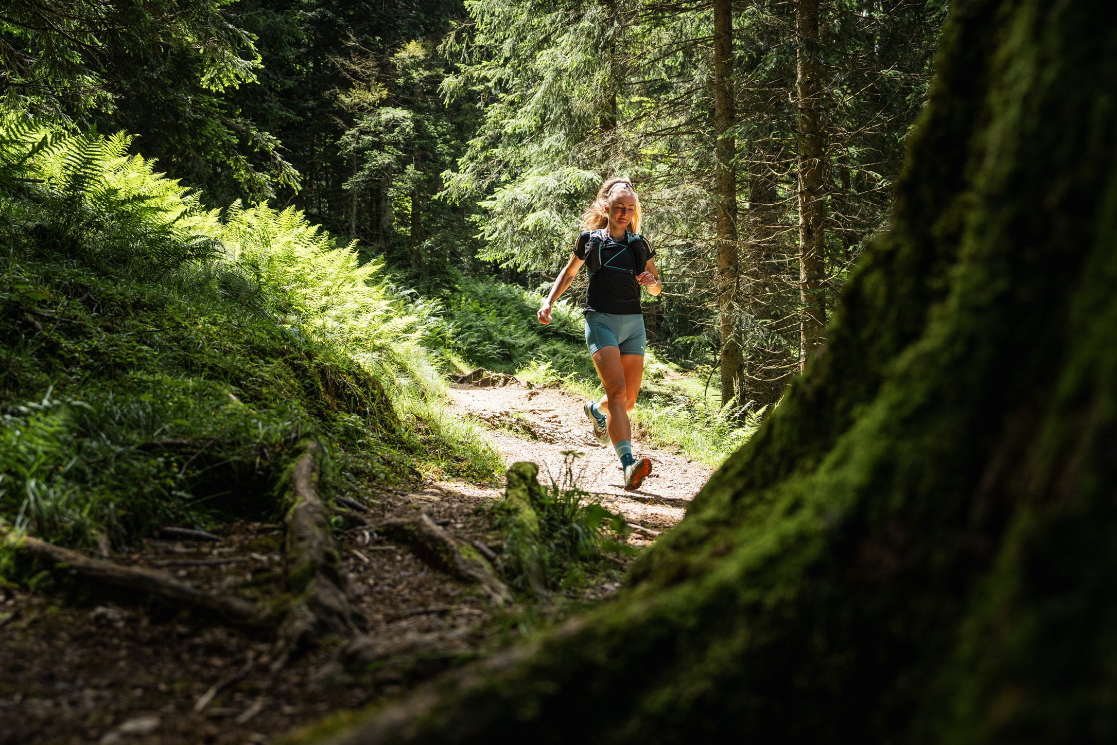 Frau beim Laufen auf einem Wanderweg im grünen Wald.
