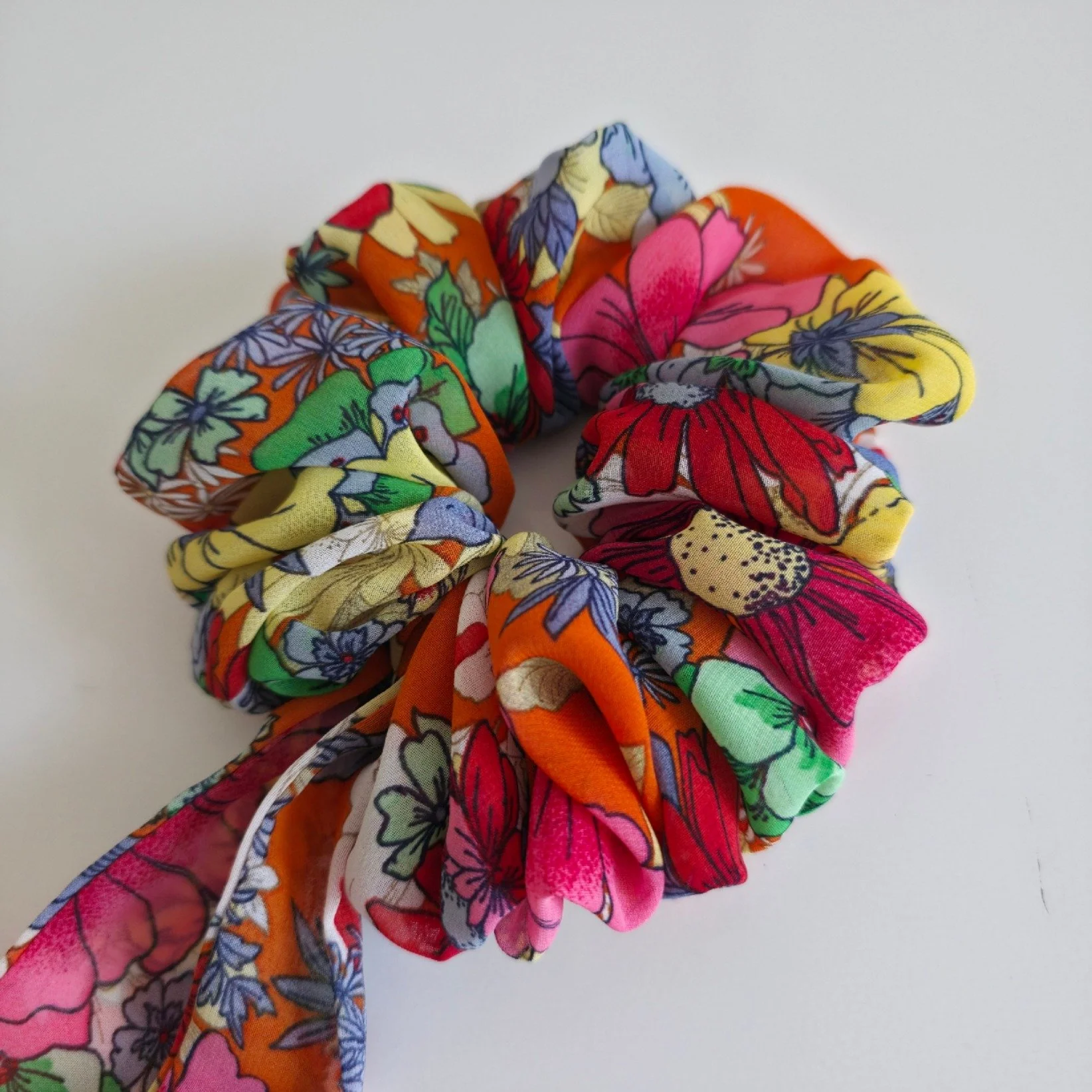 Colorful floral fabric scrunchie against a plain white background.