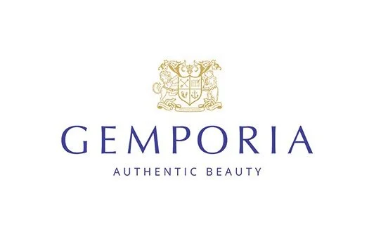 Gemporia logo with a gold crest above the words 'Gemporia Authentic Beauty' in purple text.