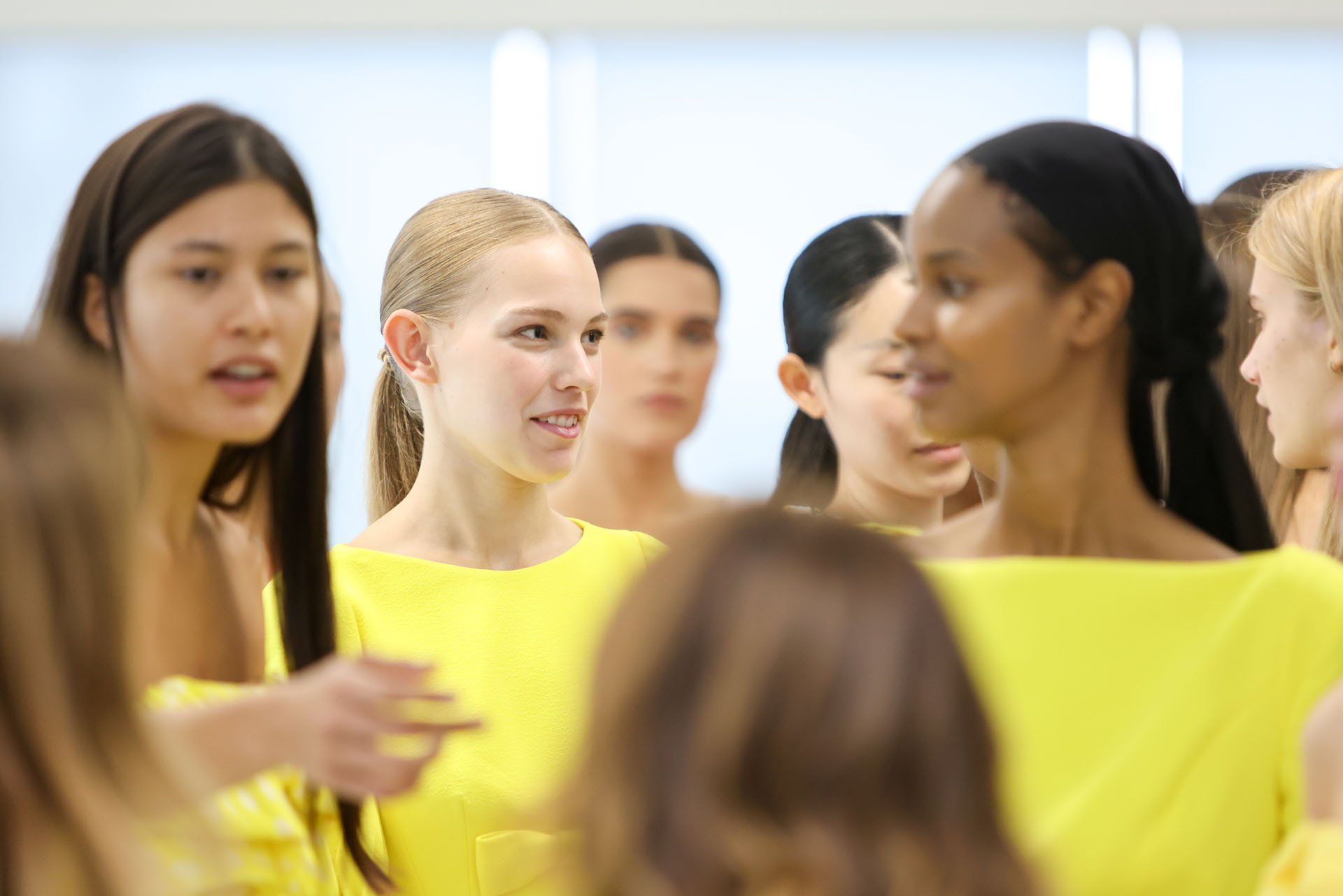Group of women in yellow outfits engaged in conversation at a social or professional event.