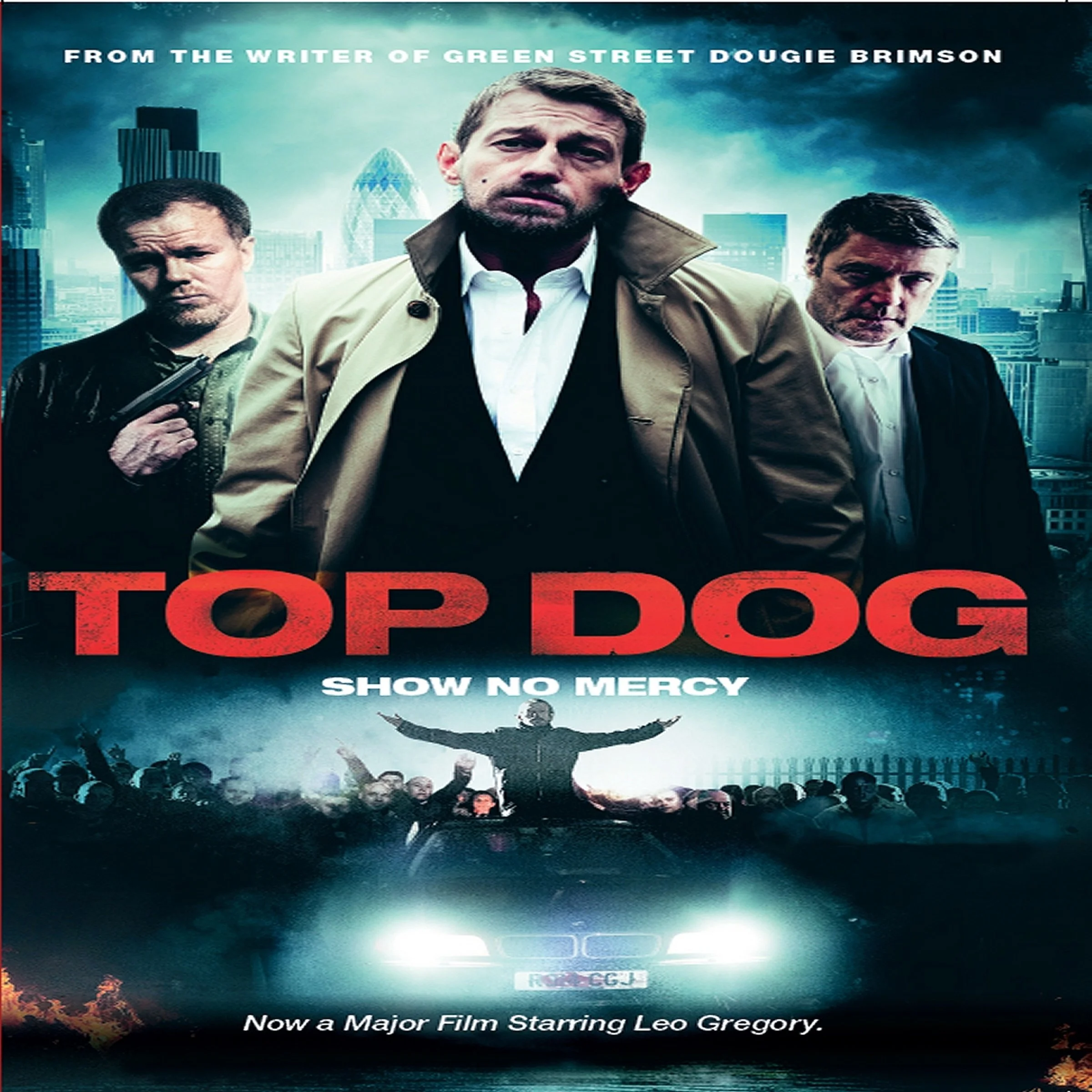 The image is a poster for the movie 'Top Dog.' The poster features three men, with the central figure being a man with a serious expression, wearing a tan trench coat and a white shirt. The other two men flanking him have stern expressions, one holding a gun. The background shows a city skyline with tall buildings under a cloudy sky. The poster includes text indicating that the film is from the writer of 'Green Street' Dougie Brimson, stars Leo Gregory, and has a tagline 'Show No Mercy.' The bottom of the poster has some additional text, including a reference to a major film starring Leo Gregory.