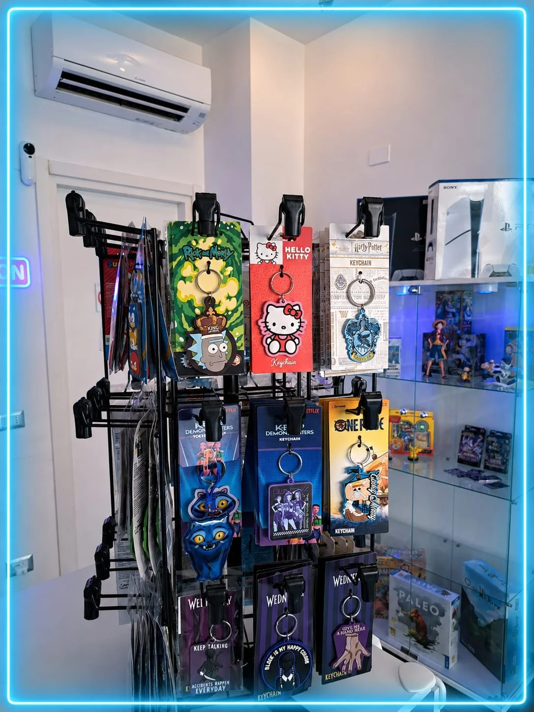 Vassoio con portachiavi di personaggi di cartoni animati e serie TV su uno scaffale, in un negozio di giocattoli o merchandising, con una scheda di plastica trasparente di supporto per i cartellini di prezzo o identificazione.