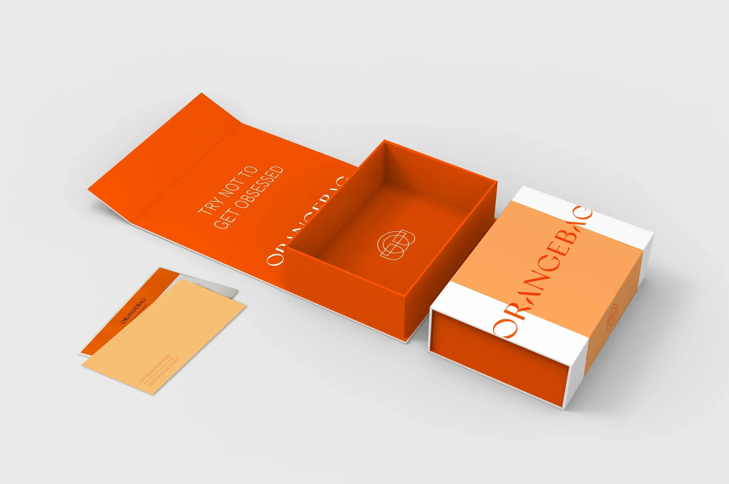 Open orangebag box with the phrase "Try Not To Get Obsessed" inside, and a matching card and strip of paper nearby on a gray surface.