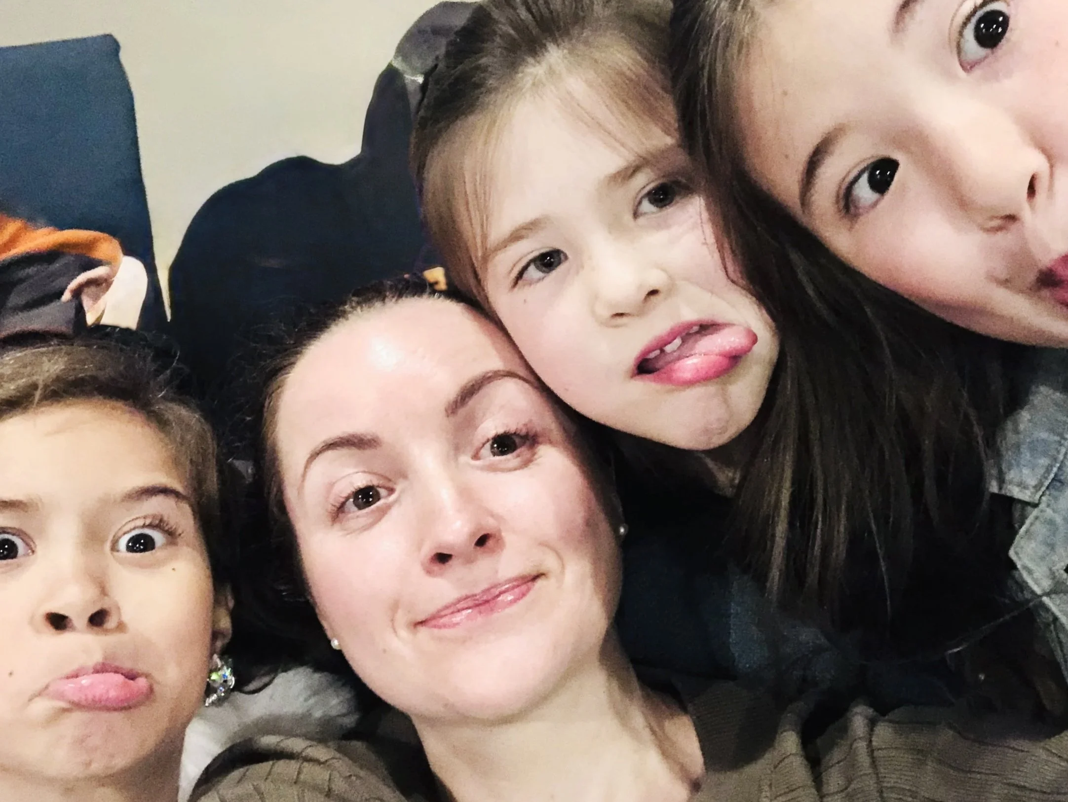 Close-up of smiling children and an adult with playful facial expressions, making faces for the camera.