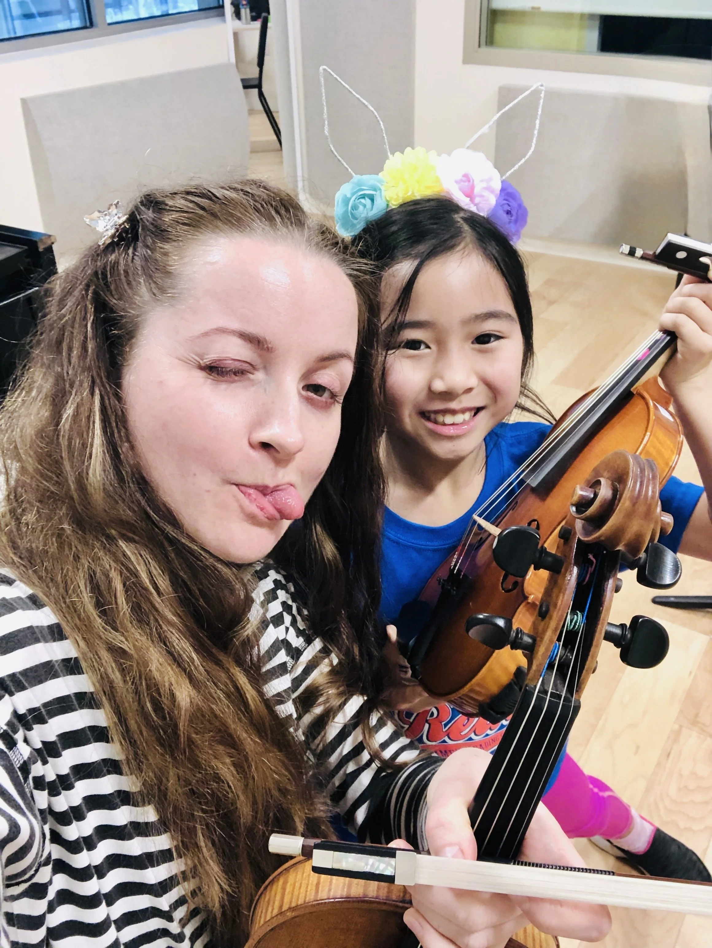 Violin teacher and young student sharing a joyful moment during a violin lesson.