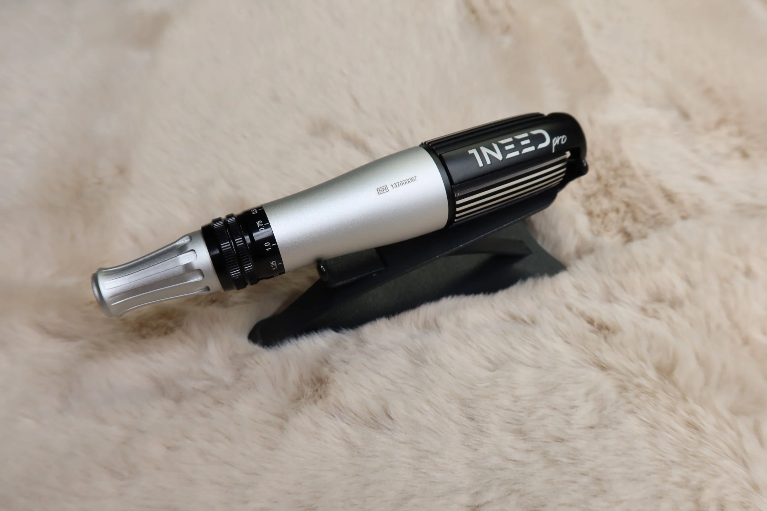 A silver and black microphone with the brand name 'INNEED' on a beige, furry surface.