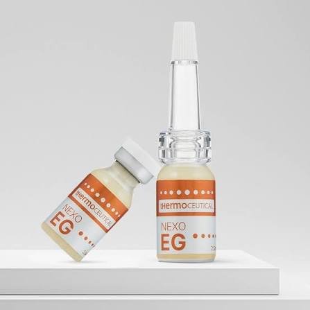 Two small glass bottles labeled 'NEXO EG' with orange and white labels, one with a white cap and the other with a long clear applicator tip, placed on a white surface against a plain gray background.