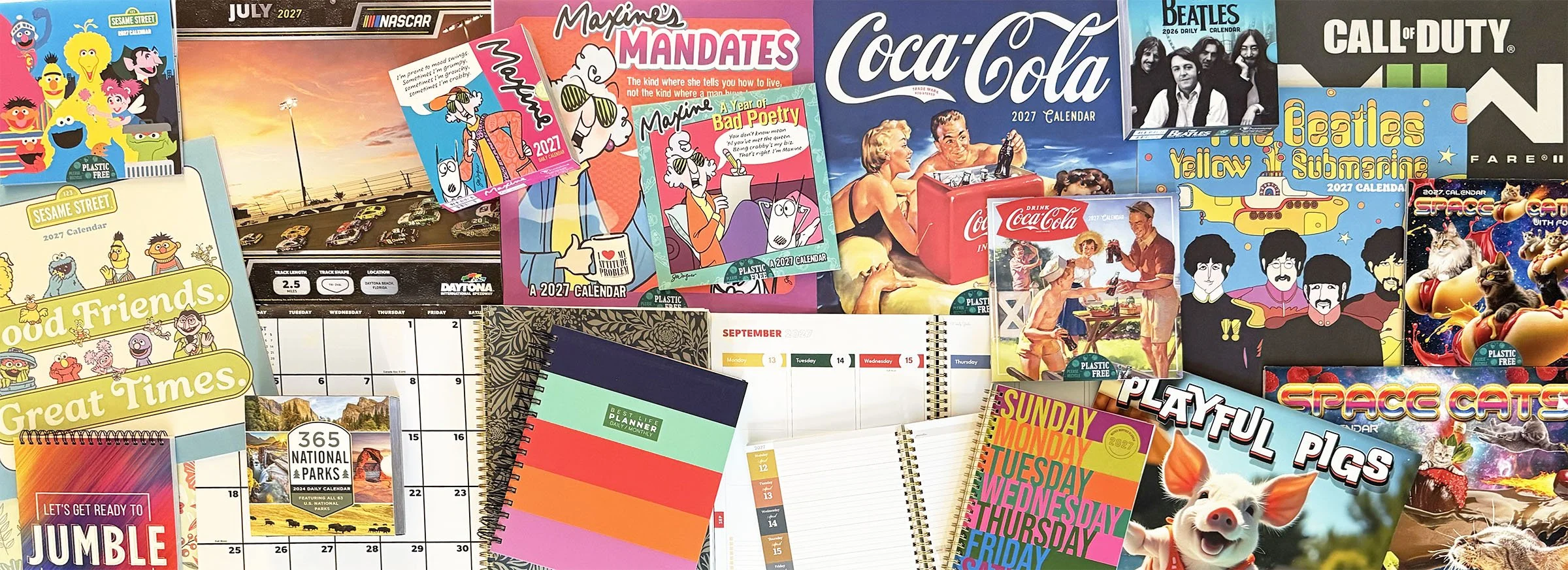 A collection of colorful 2027 calendars, planners, notebooks, and greeting cards featuring cartoon characters, animals, and pop culture images.