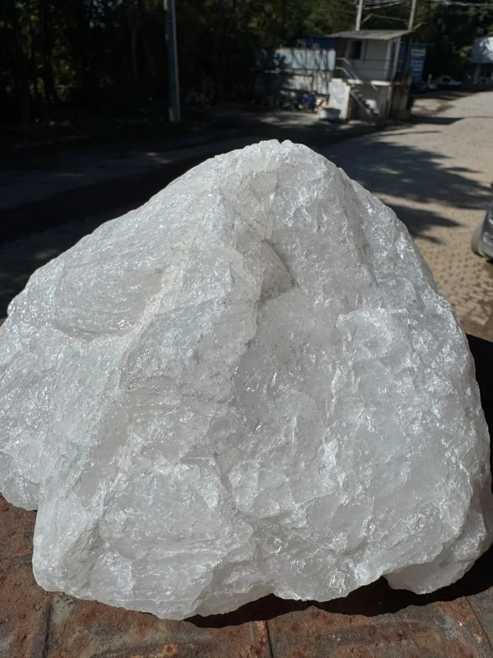 Uma grande pedra de sal branca com superfície brilhante, colocada sobre um piso de tijolos.