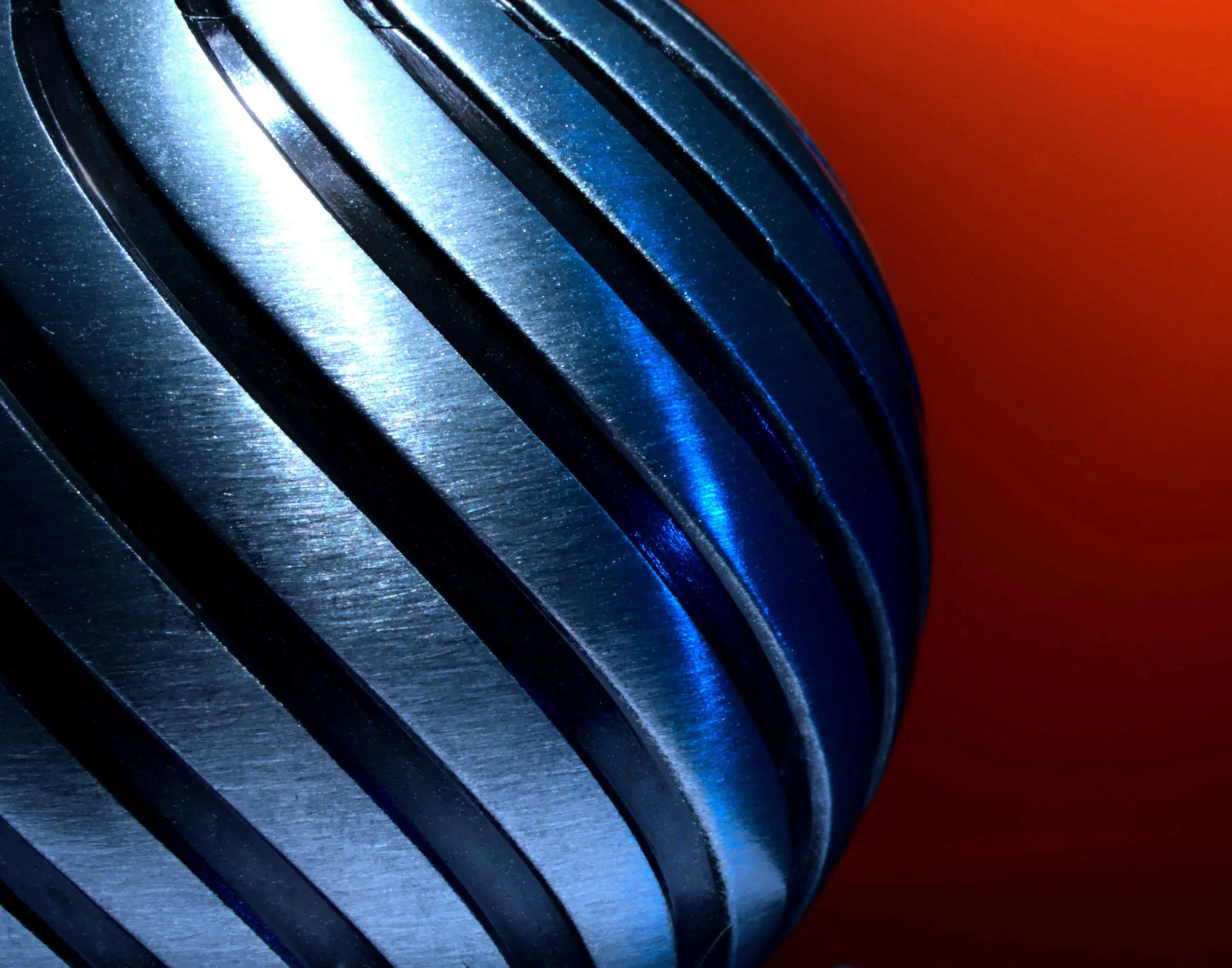 Close-up of a metallic gear with curved teeth, with a red background.