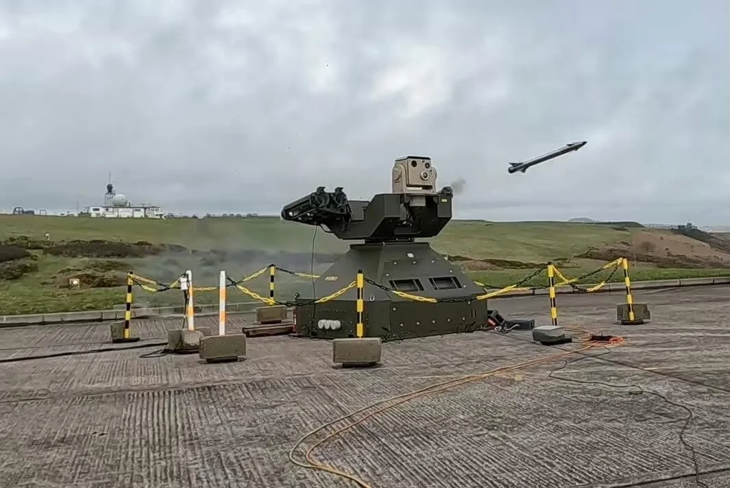 A missile launching robot with a missile flying through the air during an outdoor demonstration, with gray cloudy skies and a building with a dome in the background.