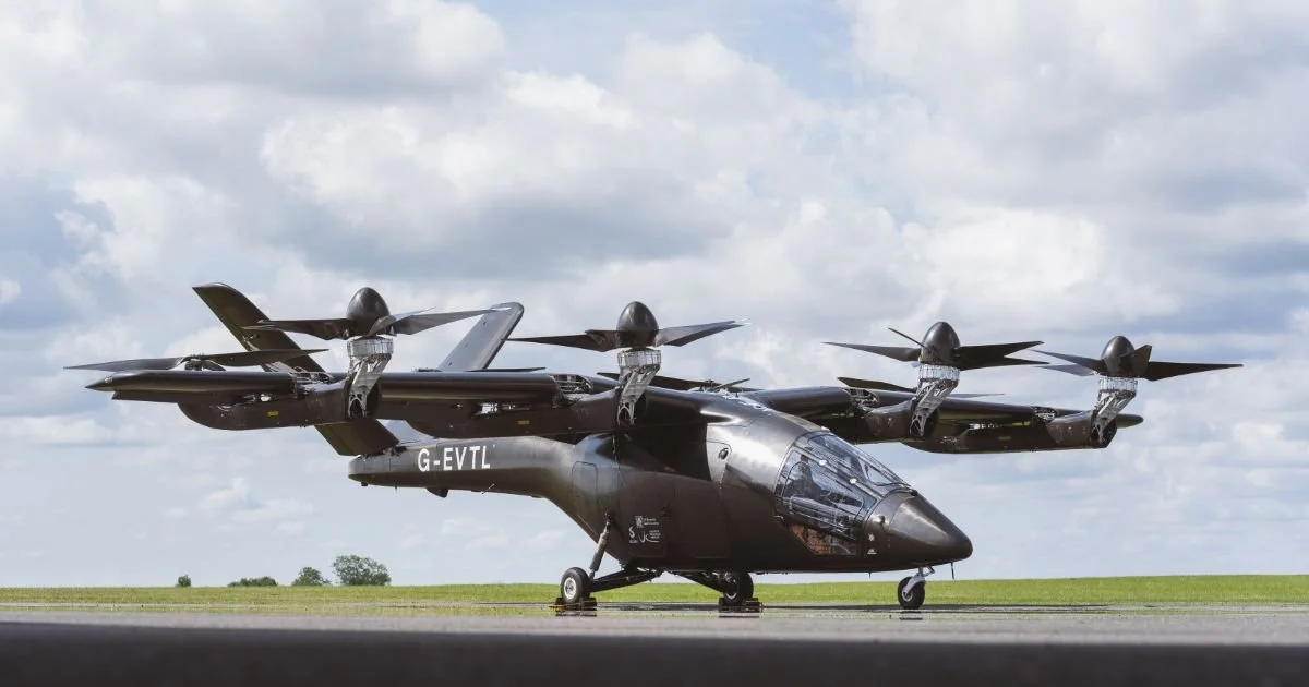 Black tiltrotor aircraft on tarmac with cloudy sky background.