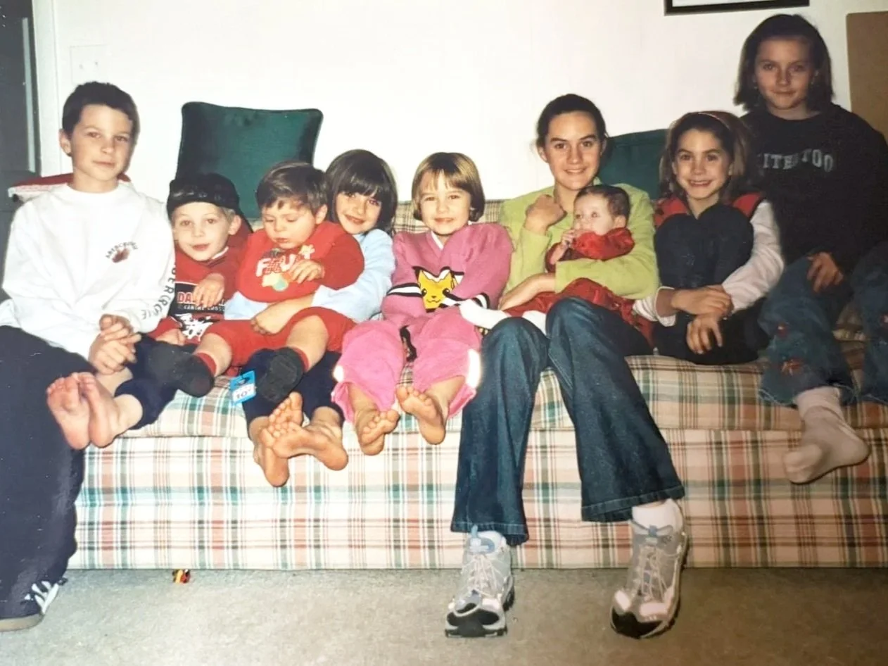Group of children sitting on a plaid sofa, smiling, indoors.