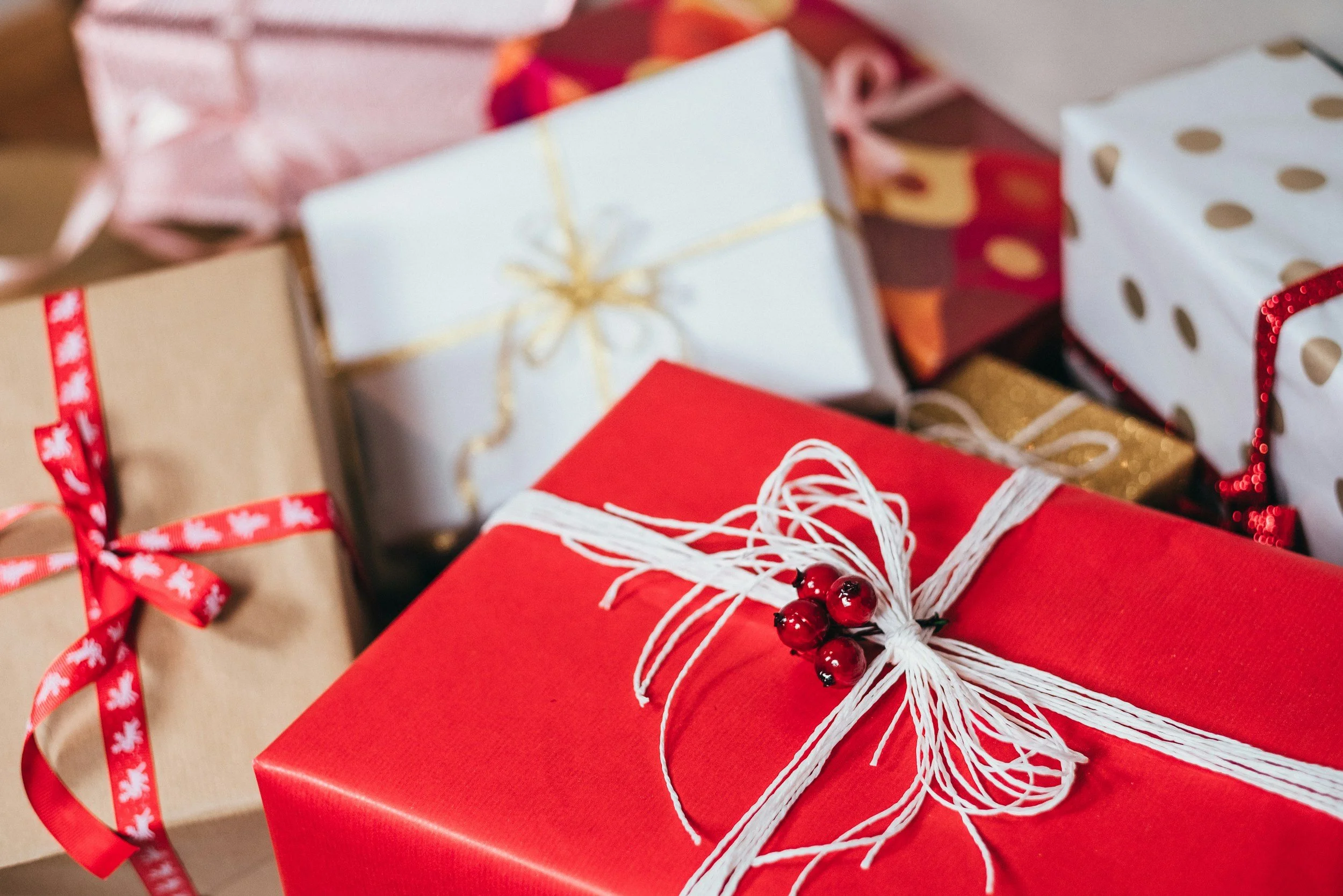 Various Christmas presents wrapped in festive paper with ribbons, bows, and decorations.