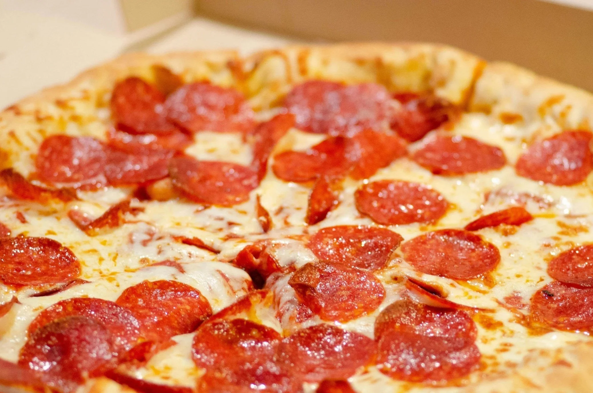 Close-up of a pepperoni pizza with melted cheese and a crust edge.
