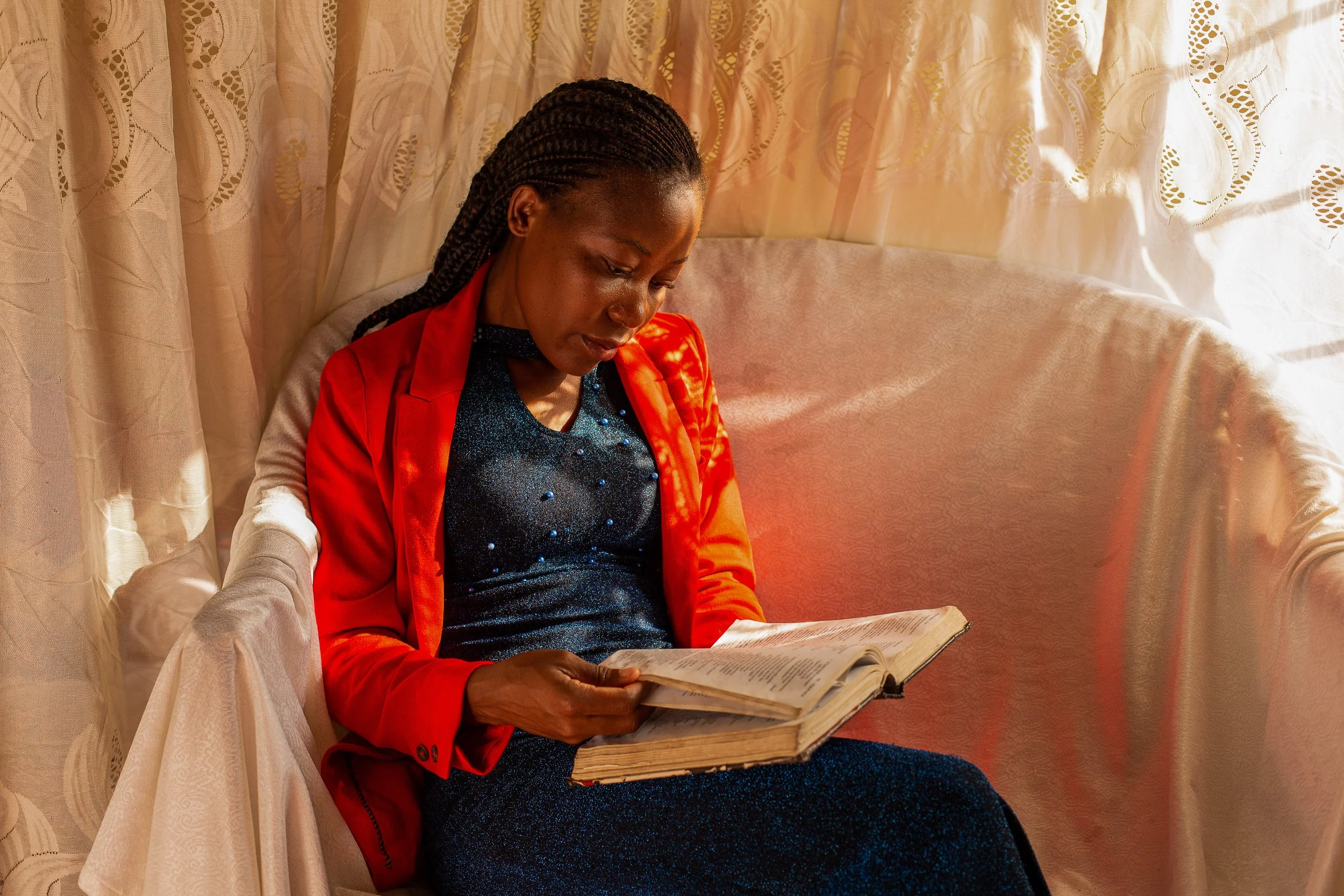 Ruth sits in a chair1 draped in white fabric reading her Bible