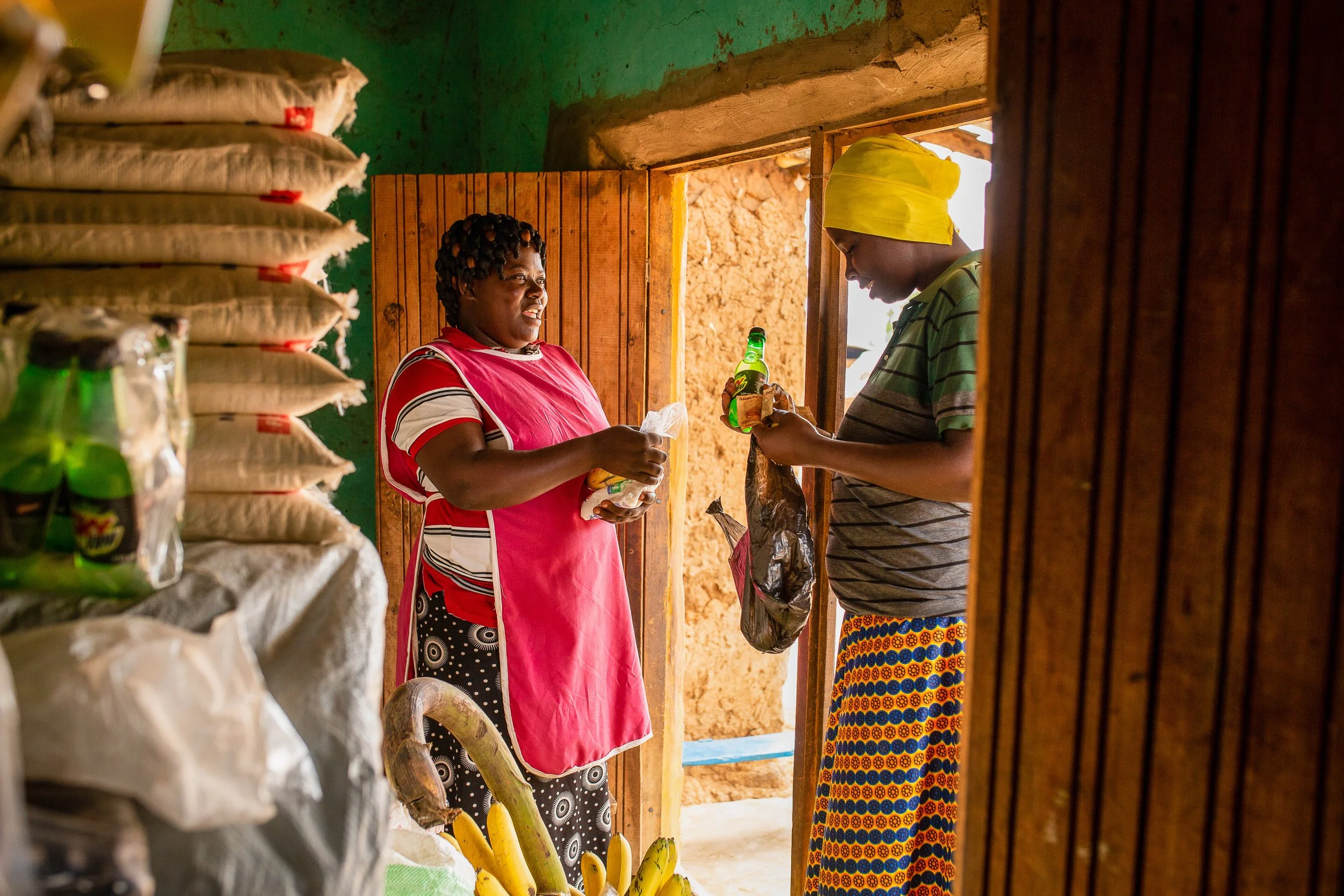 Mediatrice smiles as she serves a customer at her grocery shop