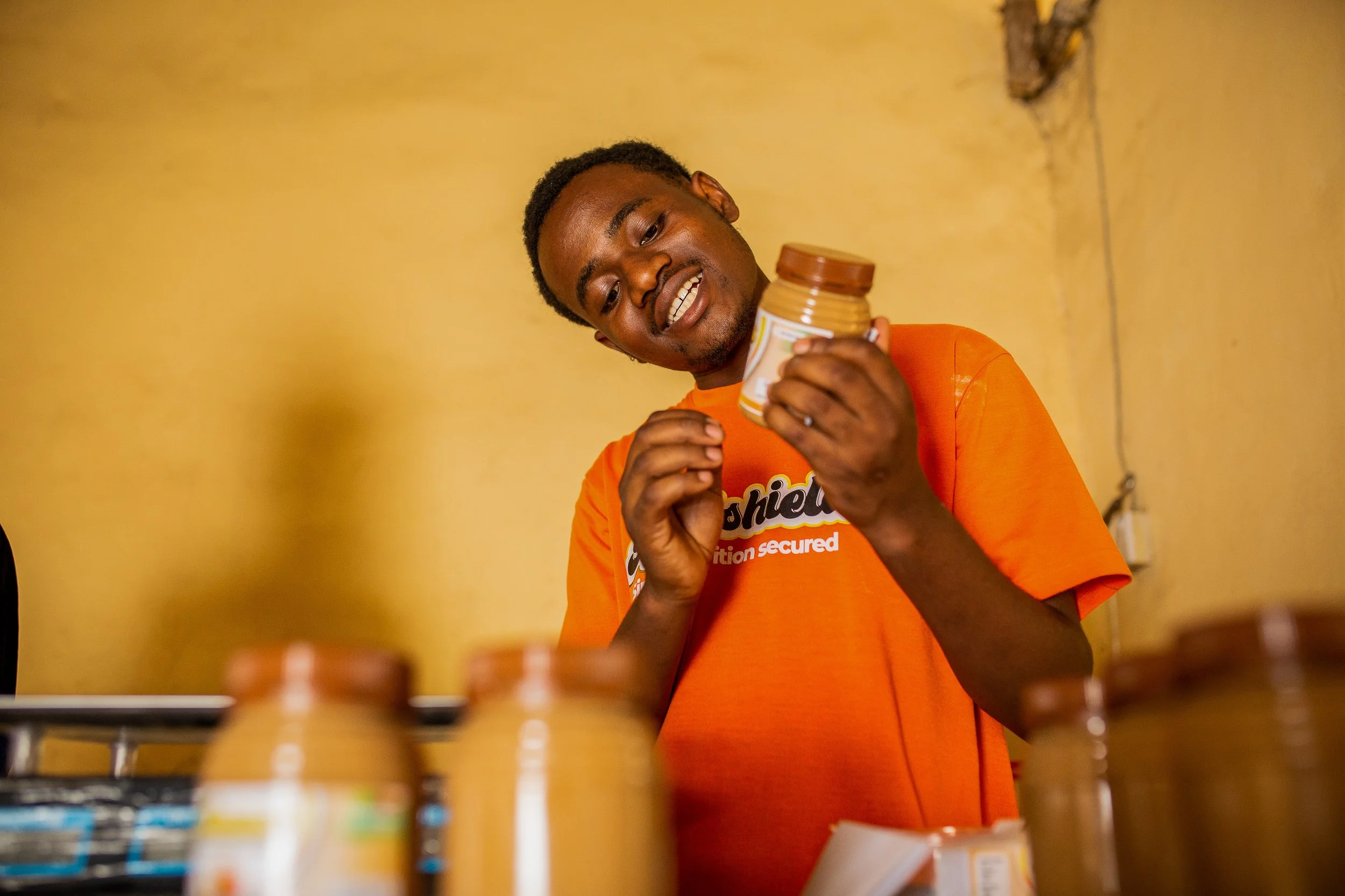 Savino stands smiling outside of his business weaning a bright orange top that says 'nutrishield'