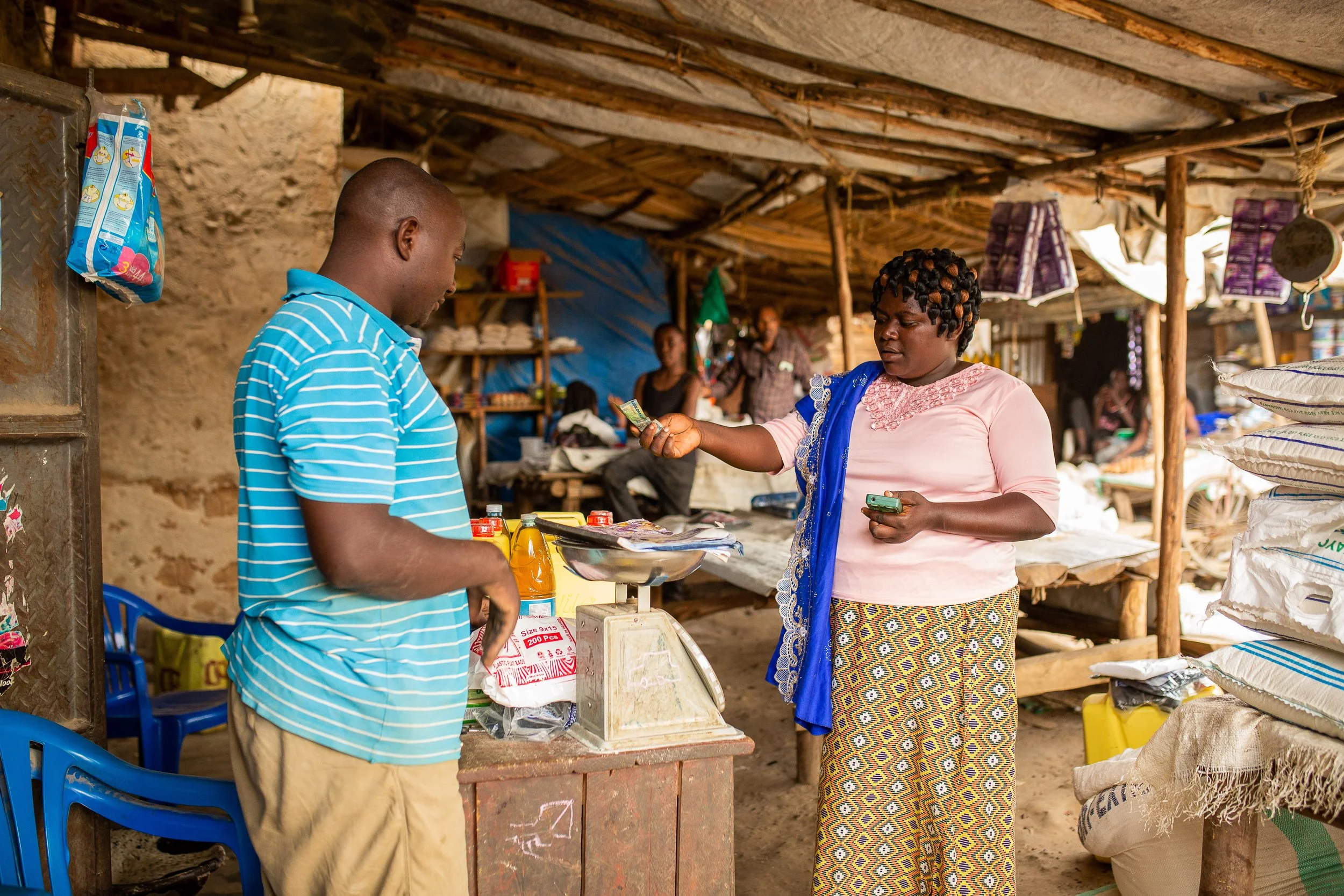 Mediatrice purchases goods at her local market for her shop.