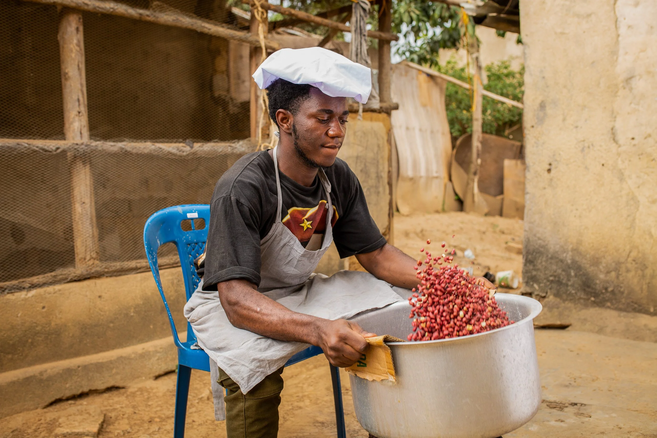 A NutriShield employee roasts peanuts outside. 