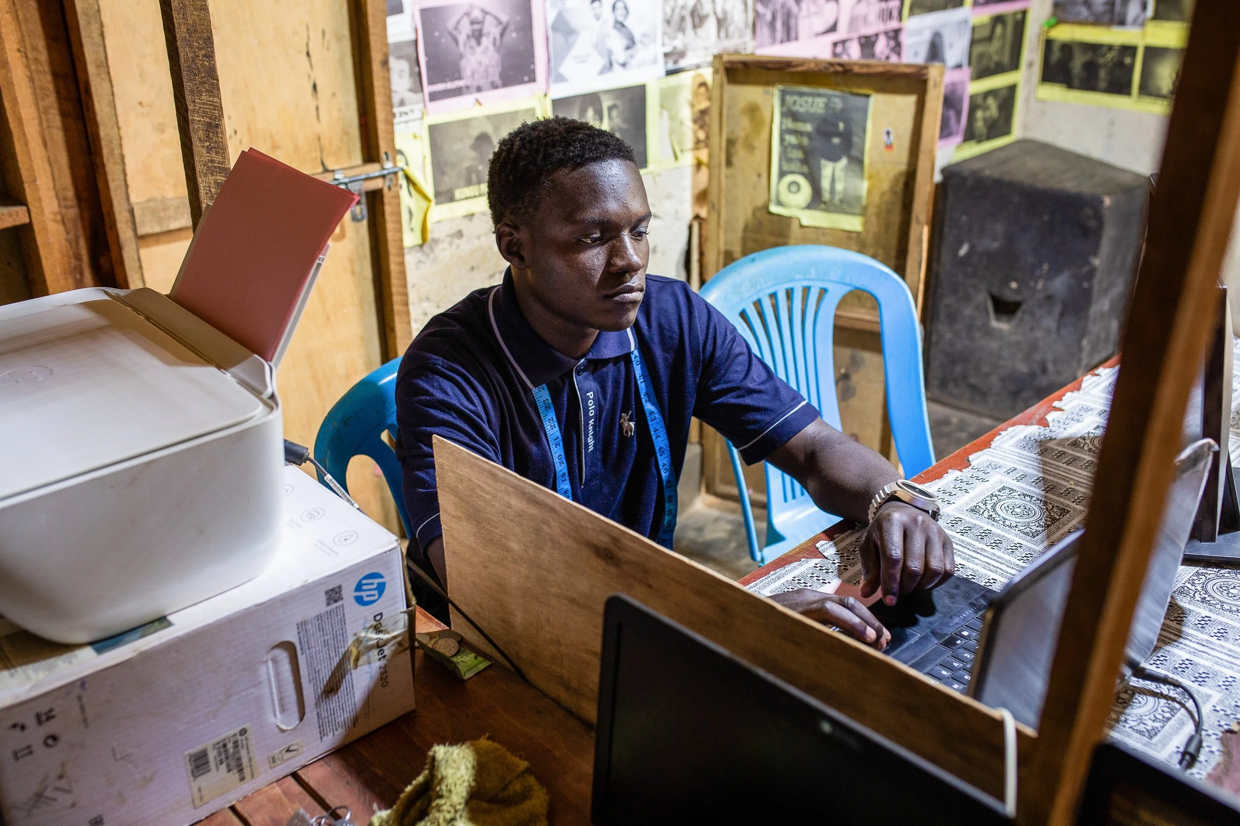 Alfred sits at his desk working on his laptop in his stationery shop