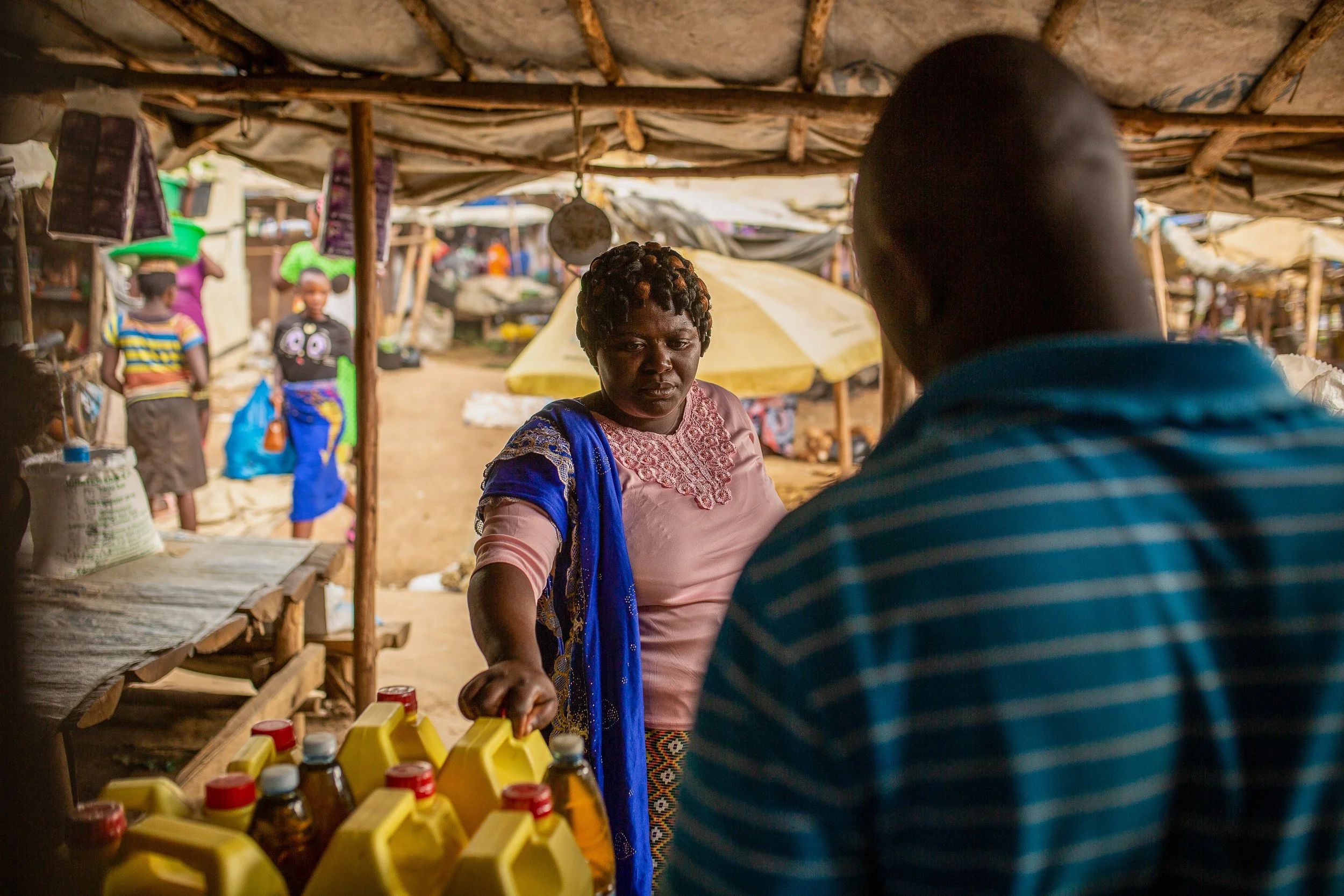 Mediatrice shops for produce to sell at her shop. Here she engages with a seller about a product. 