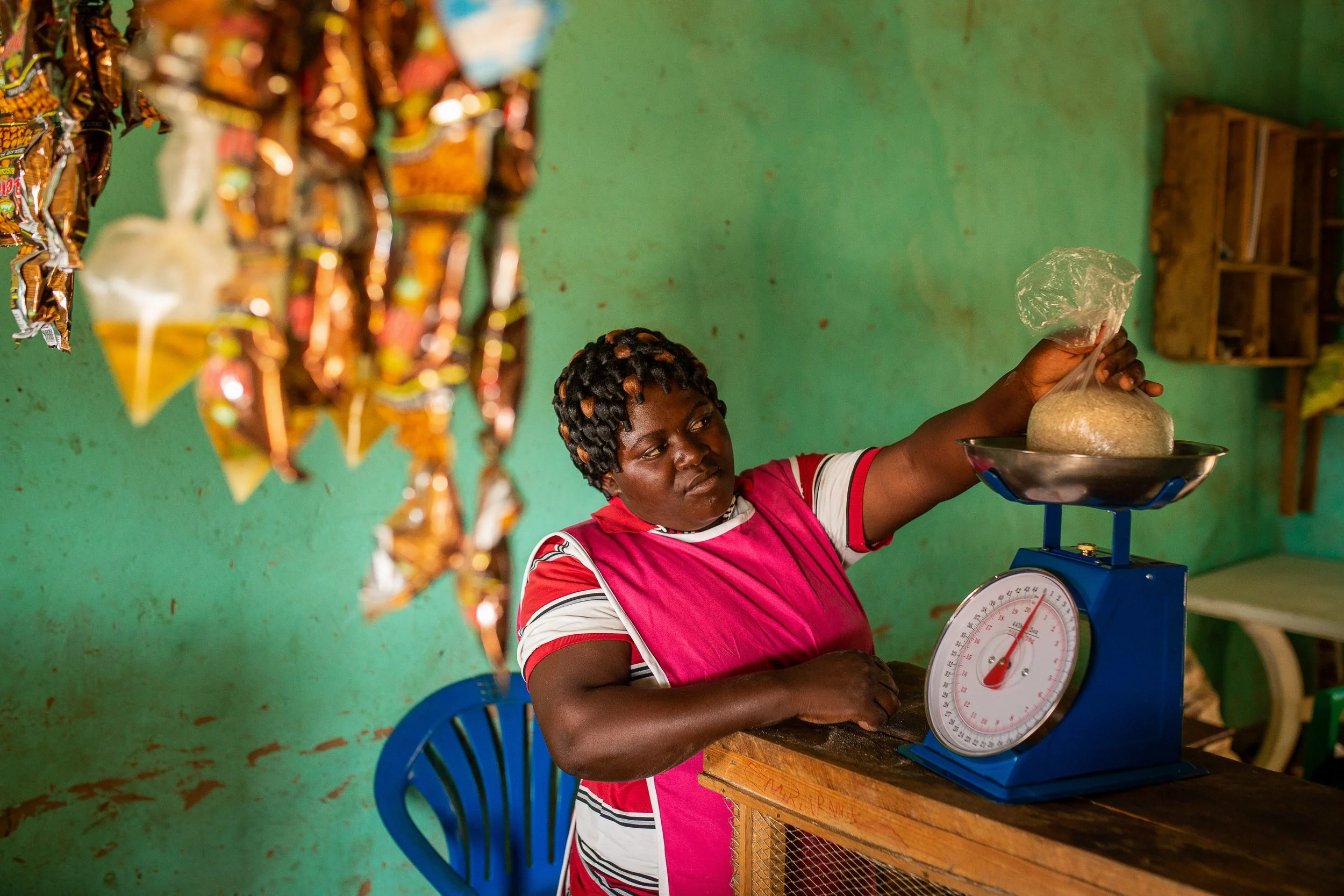 Mediatrice weighs rice in a bag in her grocery shop