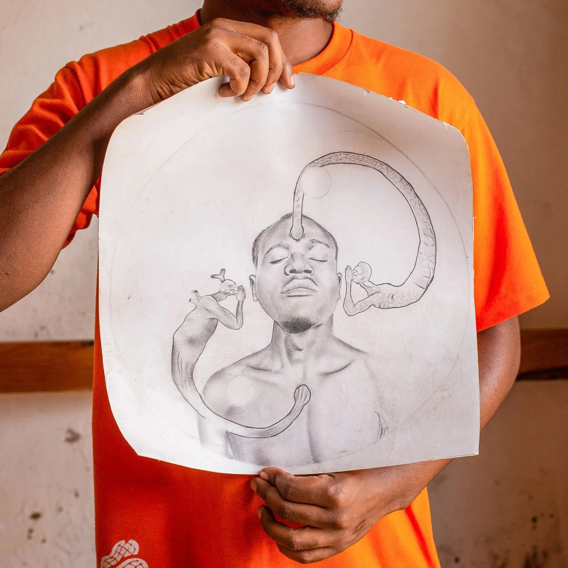 Savino holds one of his drawings. It is a pencil sketch of a man with two bodies whispering in his ear, one coming from his heart, the other from his head.