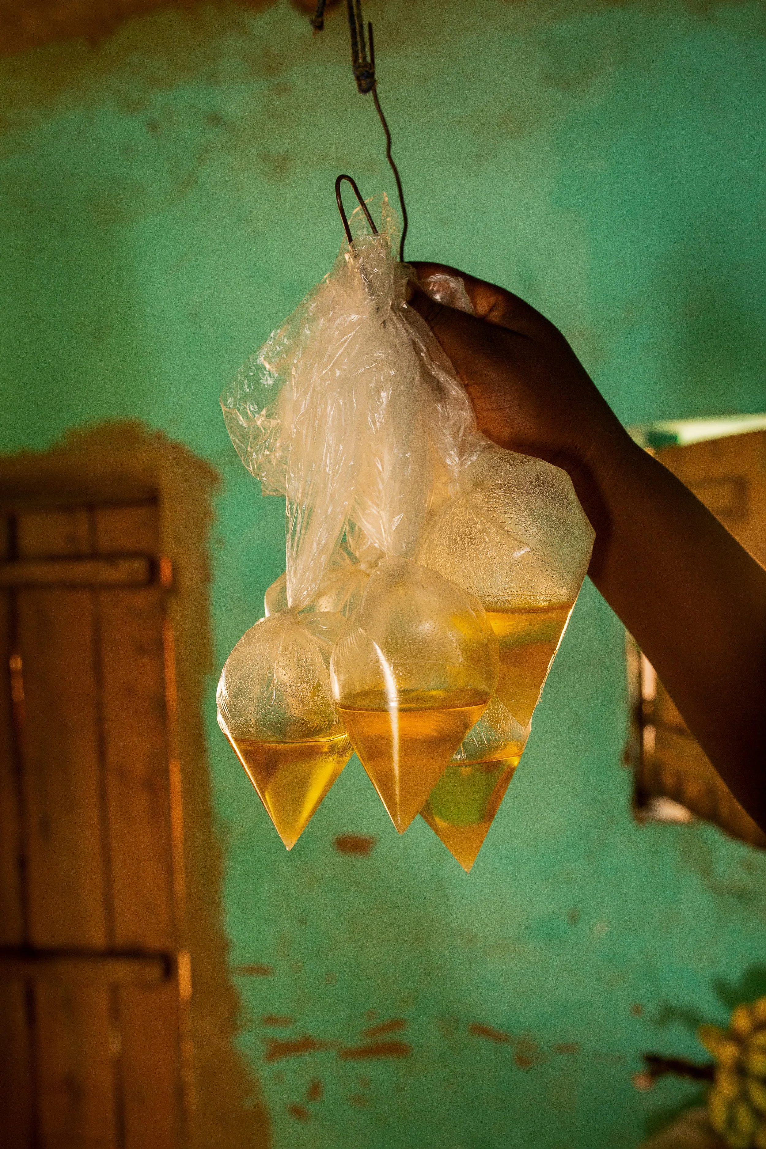 Cooking oil hangs in plastic bags from a hook in Mediatrice's shop