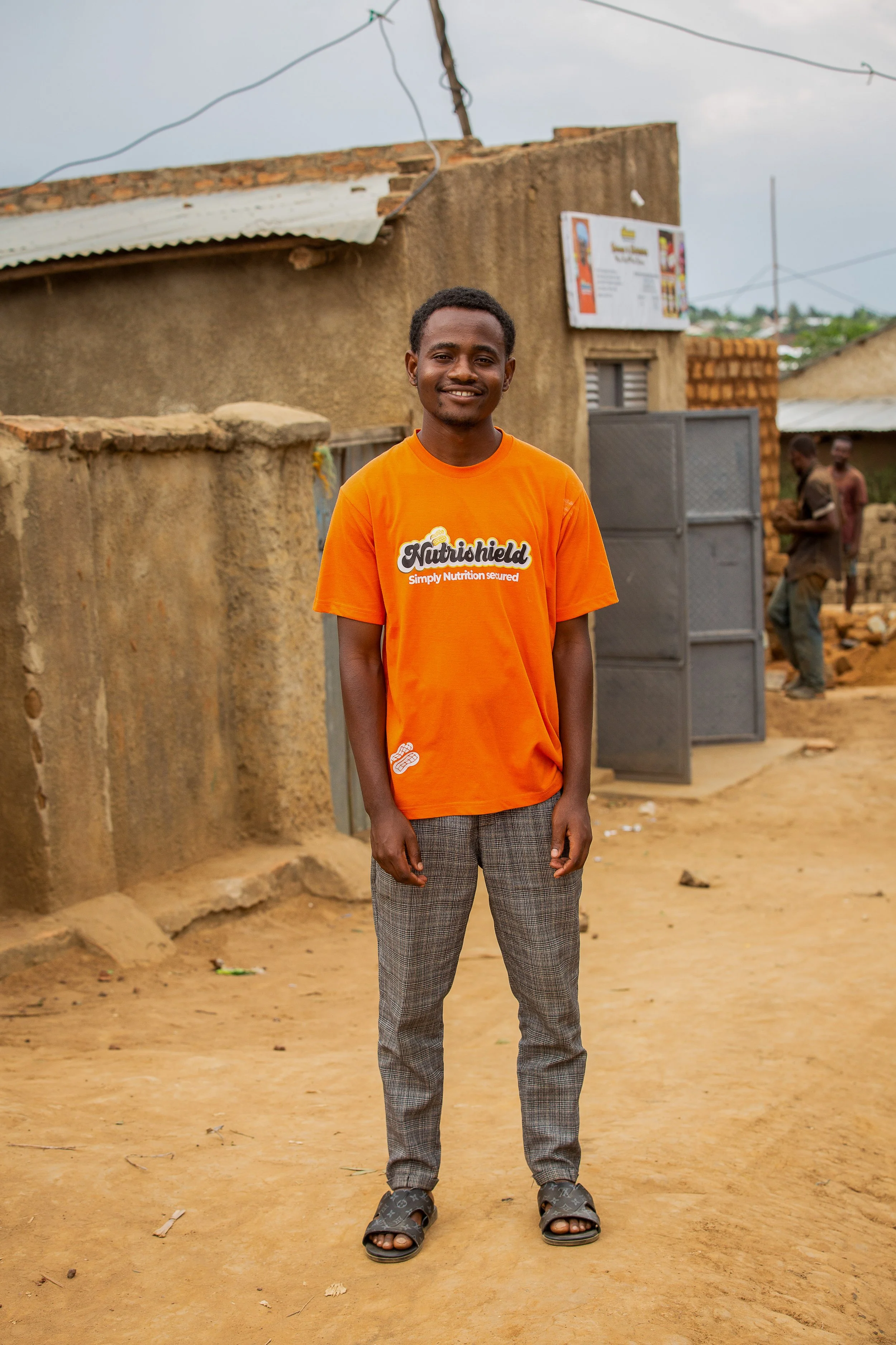 Savino stands smiling outside of his business weaning a bright orange top that says 'nutrishield'